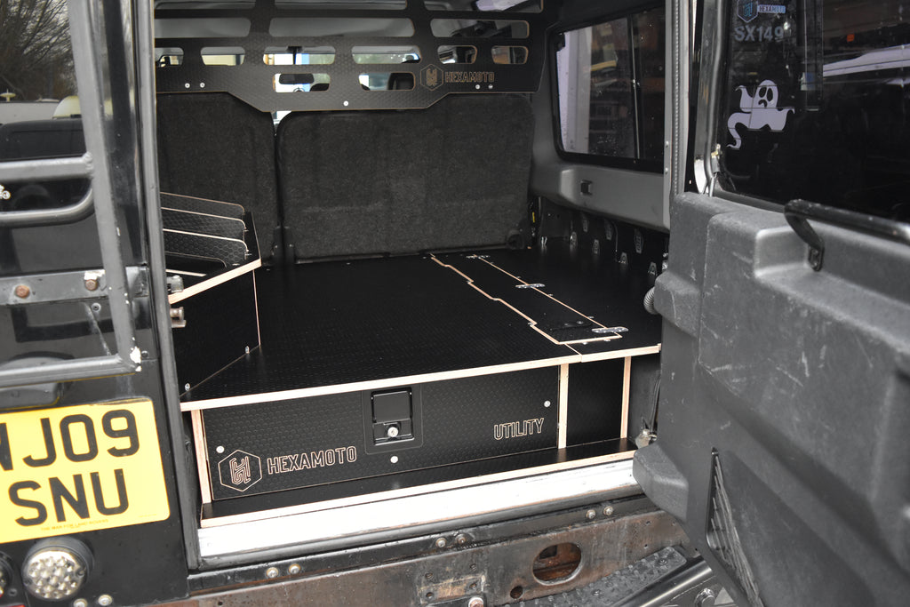 Back of a vehicle with a black cargo area and visible branding on storage system
