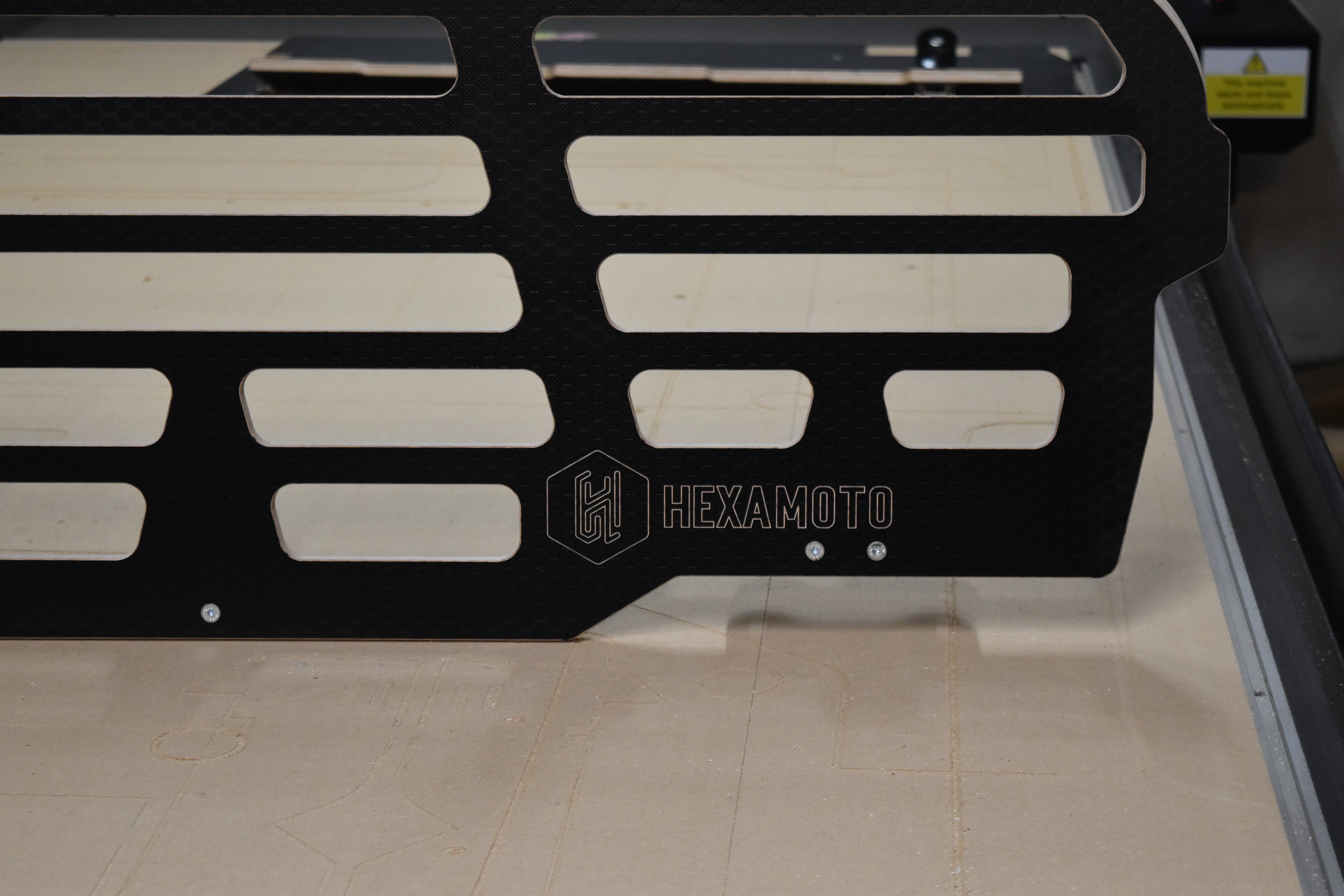Black wooden dog guard with 'Hexamoto' branding on a CNC bed
