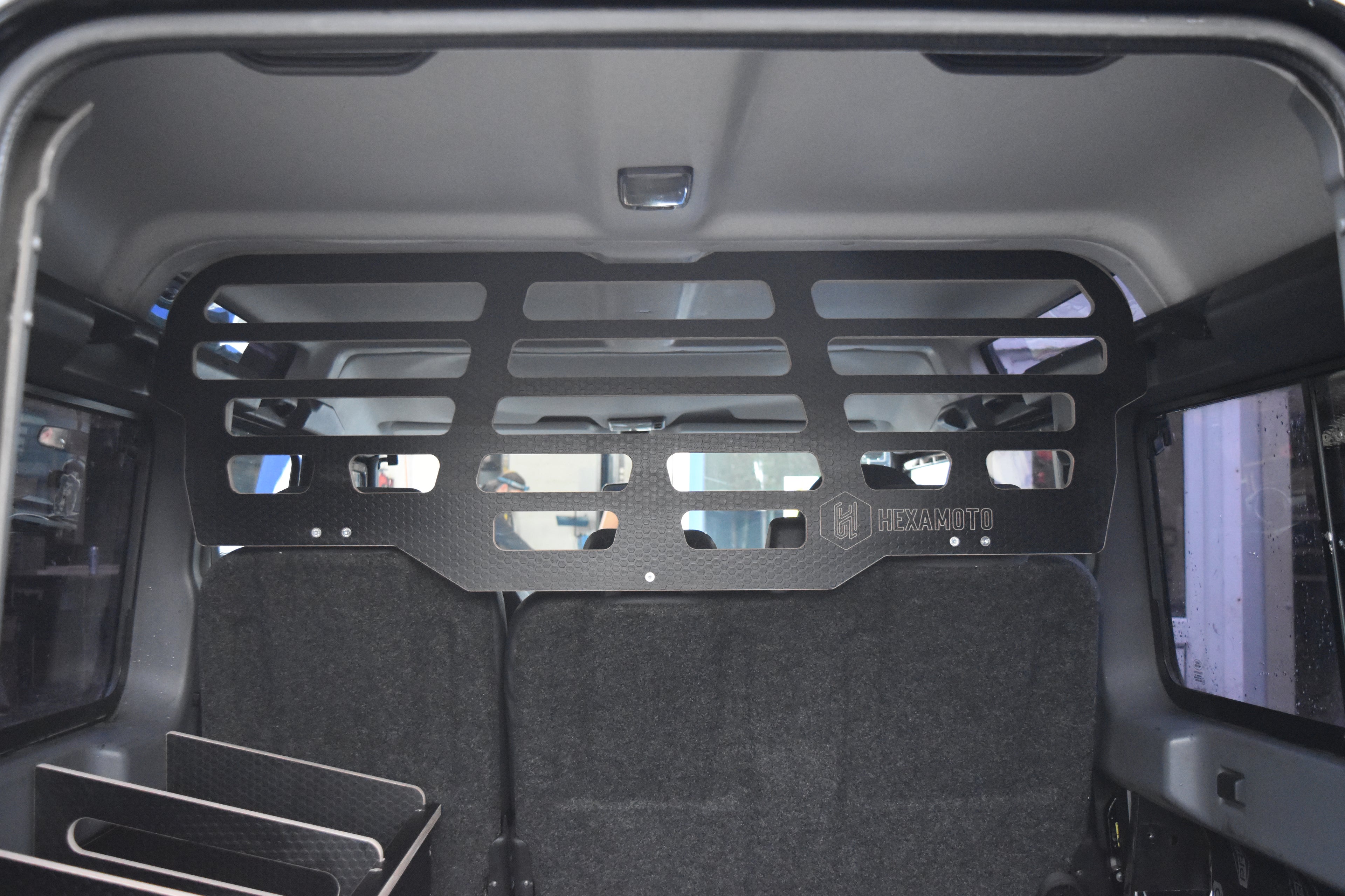 Back of a vehicle with a black wooden Hexamoto Dog Guard installed 