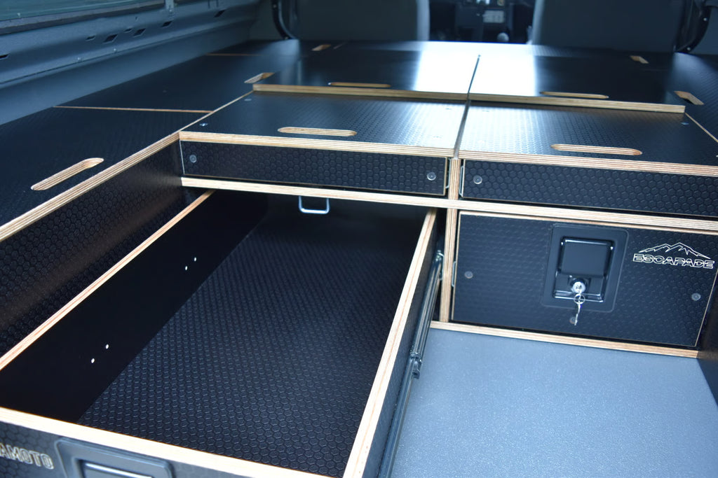 Open storage compartments with textured surfaces and a visible brand logo on a Defender interior