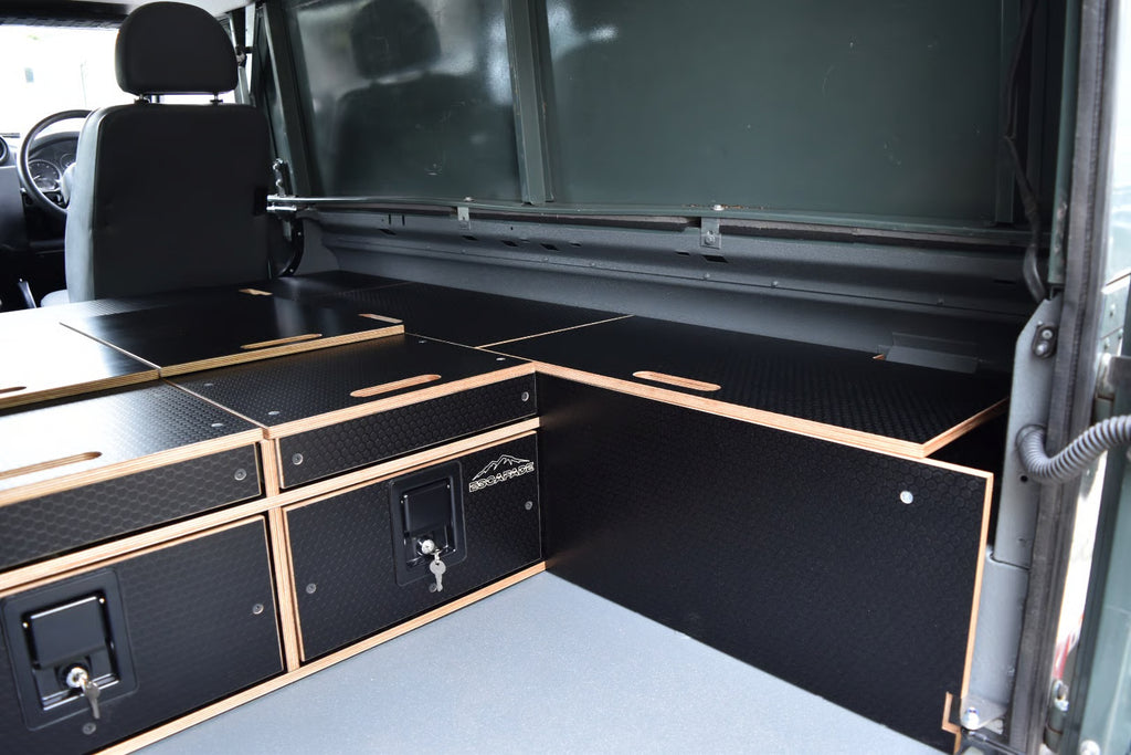 Defender 110 Utility interior with storage compartments and a bed setup.