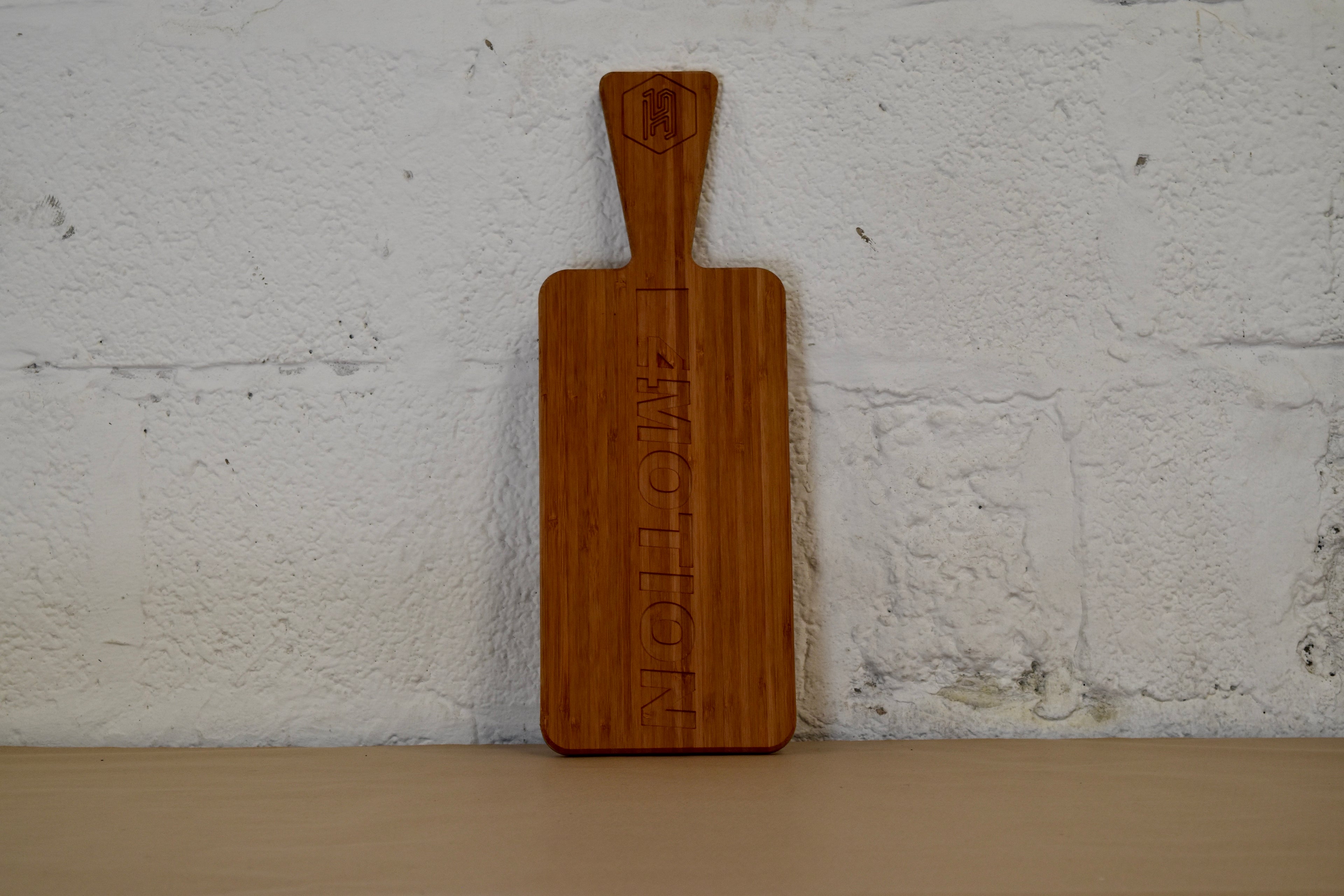 Wooden cutting board with '4motion' engraving on a white brick wall background