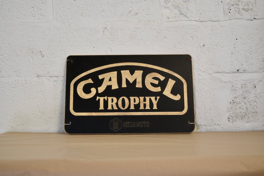 Camel Trophy table on a wooden shelf with a white brick wall background