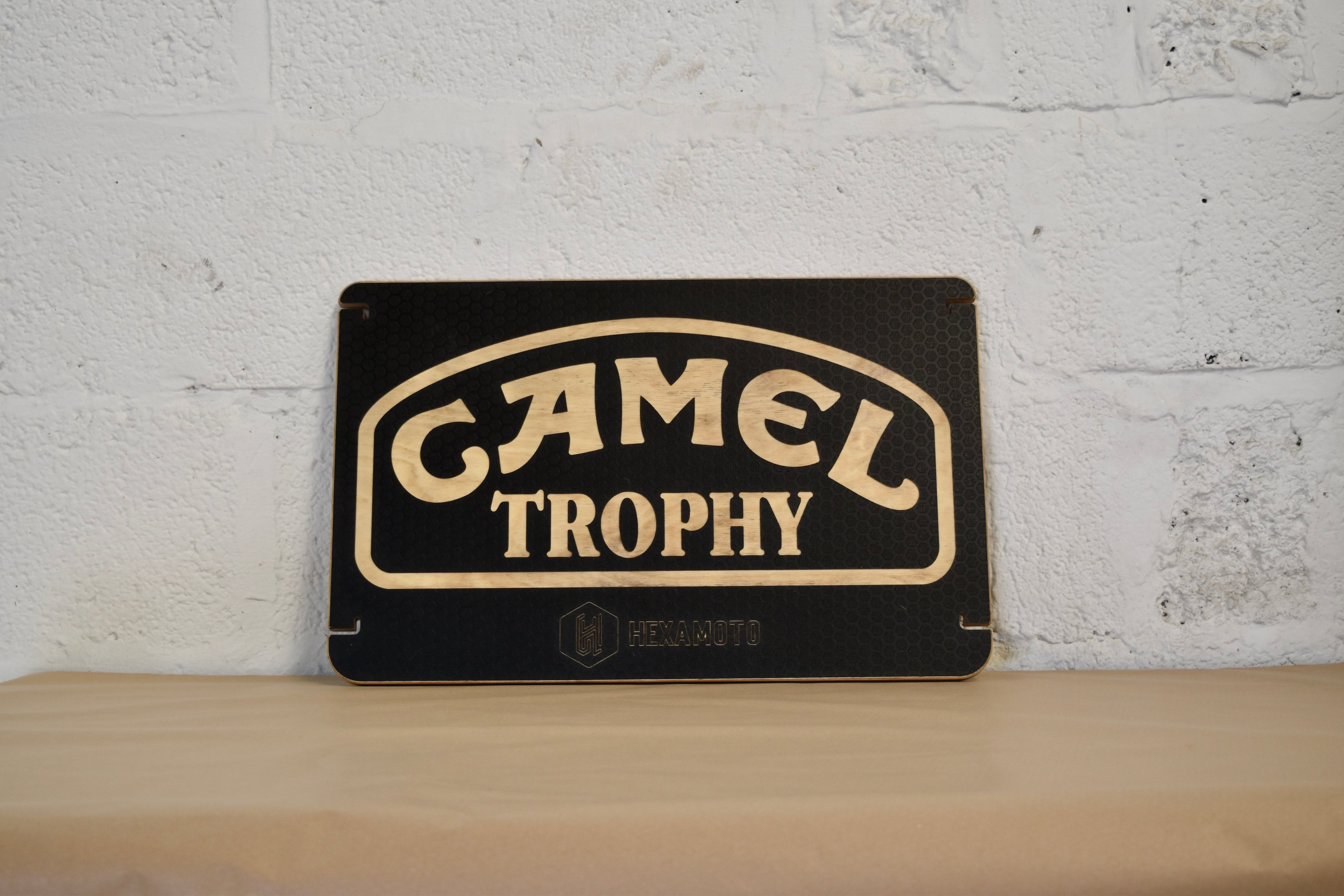 Camel Trophy table on a wooden shelf with a white brick wall background