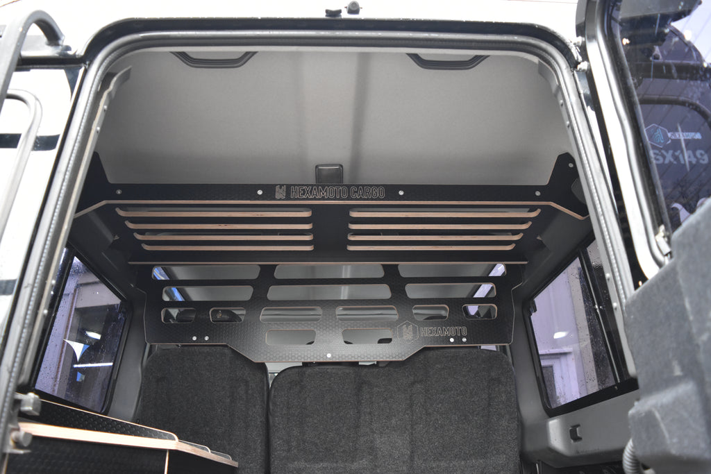 Open Defender 110 boot with a wooden cargo rack inside, showing 'Hexamoto Cargo' branding.
