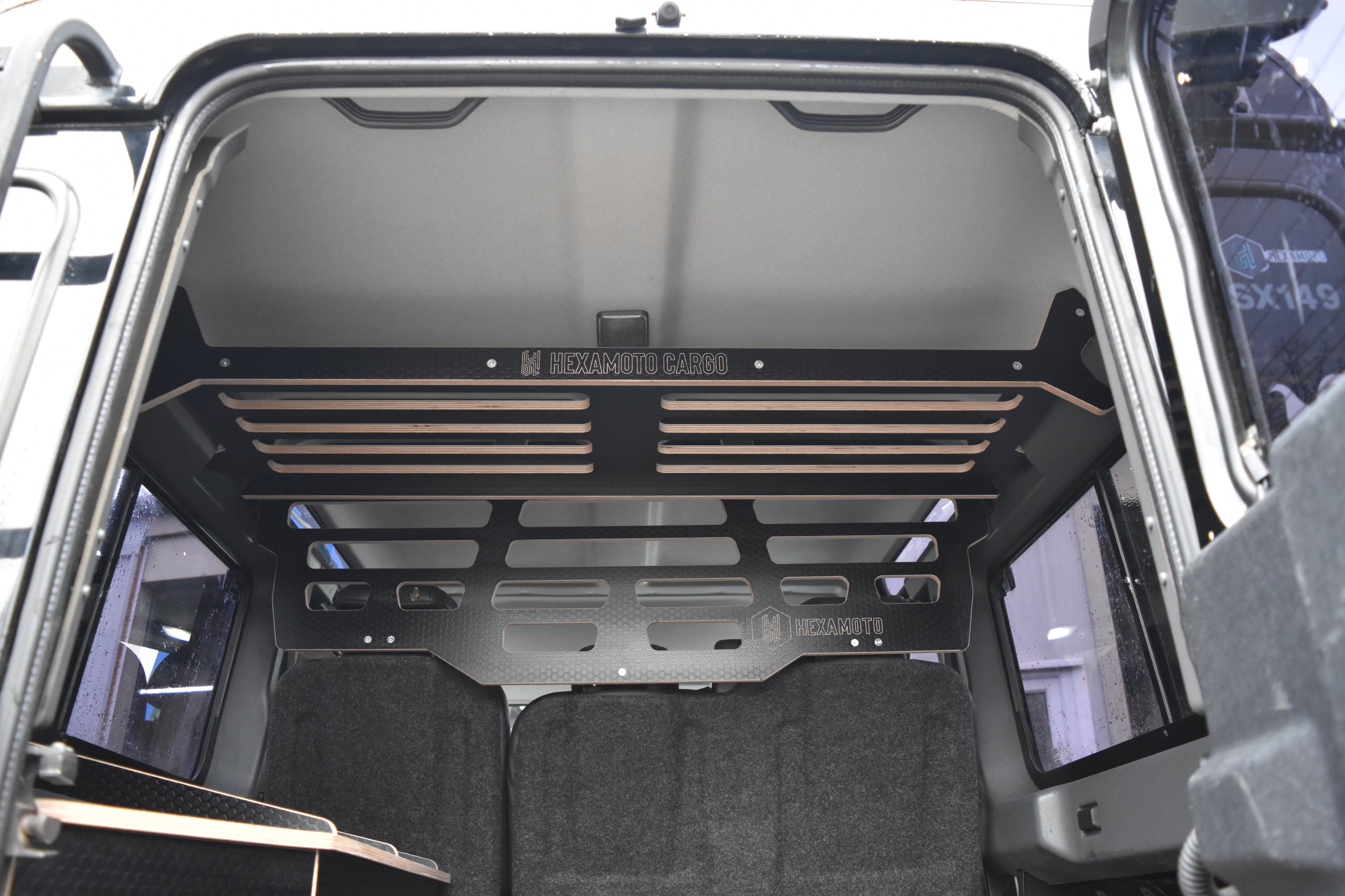 Open Defender 110 boot with a wooden cargo rack inside, showing 'Hexamoto Cargo' branding.