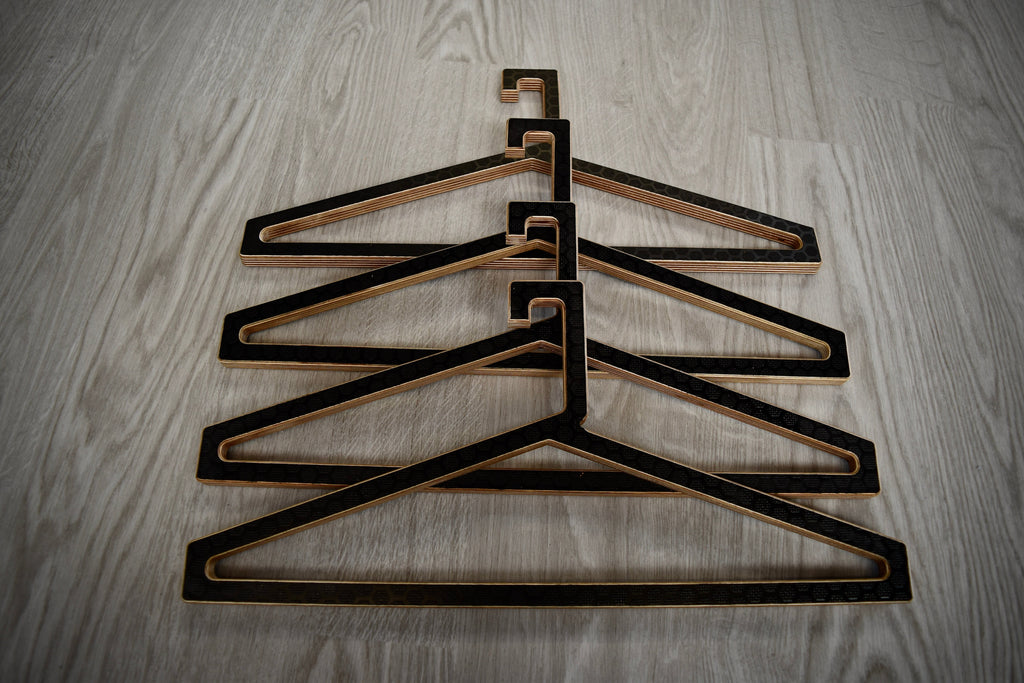 Set of black wooden hangers stacked on a wooden surface