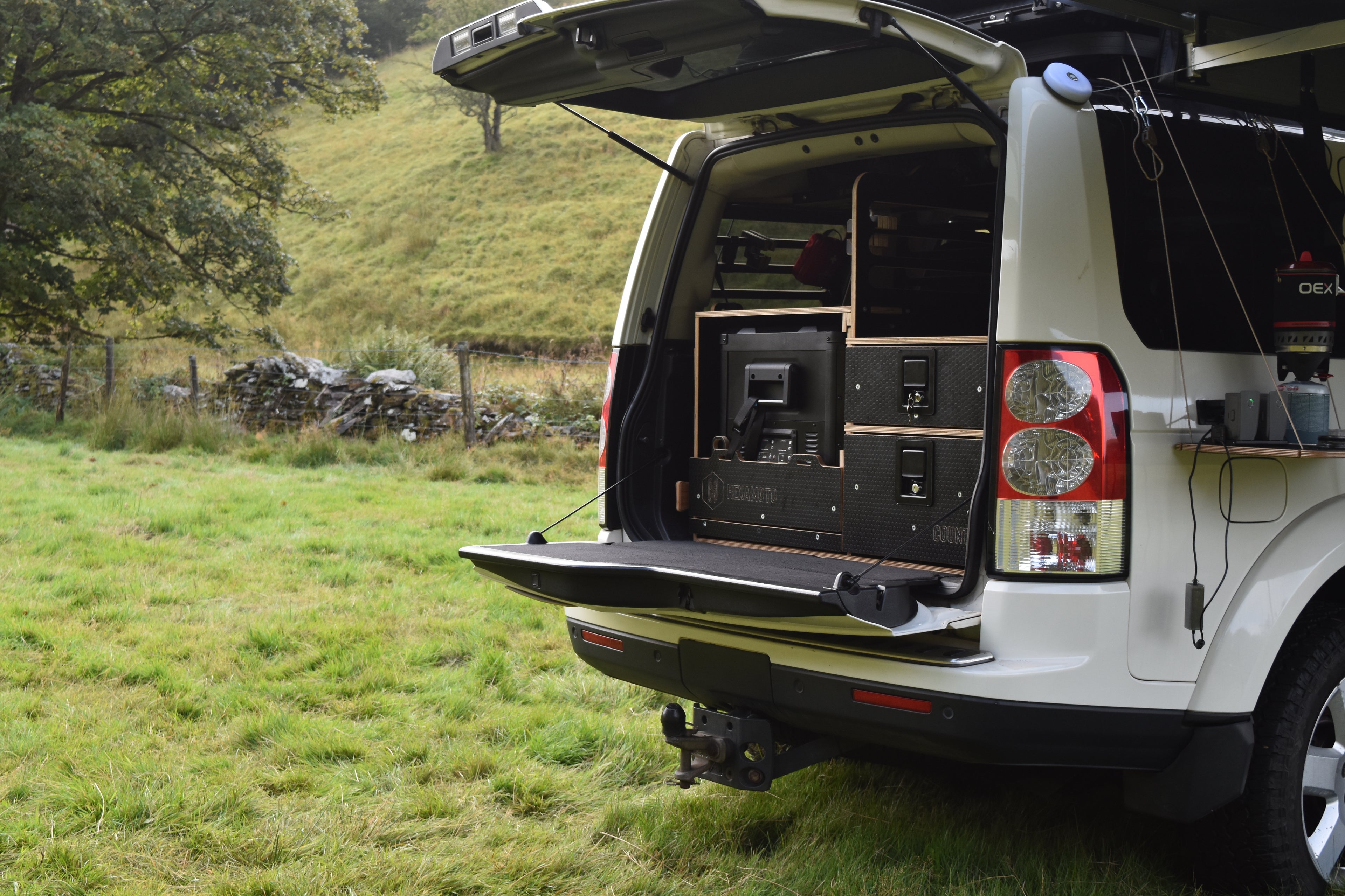 Car with boot open, showing the Hexamoto Country system in a grassy field