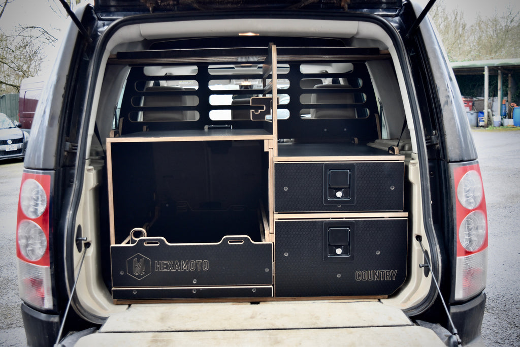 Car with open boot showing black storage units labeled 'Hexamoto Country'.