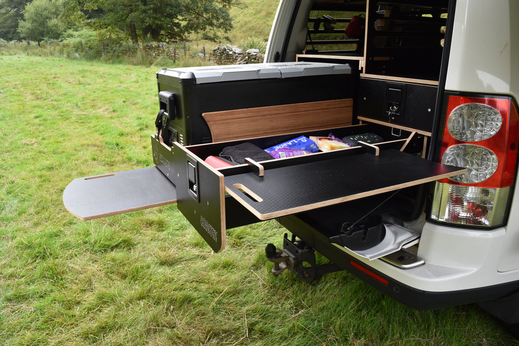 Vehicle with an extended storage compartment in a grassy outdoor setting