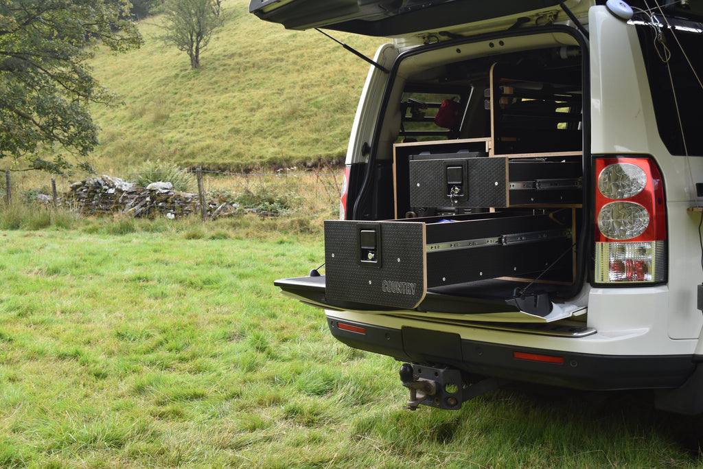 Discovery 4 truck with open cargo area in a grassy field, showing storage system fitted to the rear