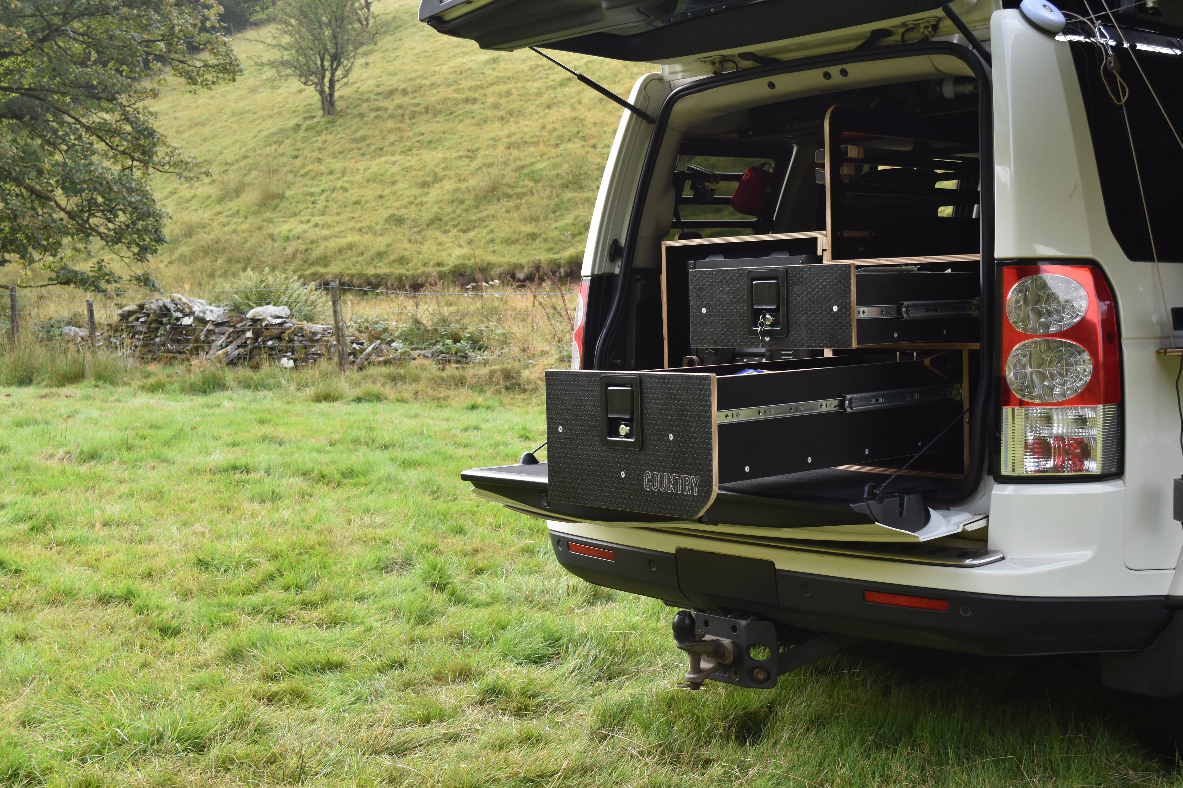 Discovery 4 truck with open cargo area in a grassy field, showing storage system fitted to the rear