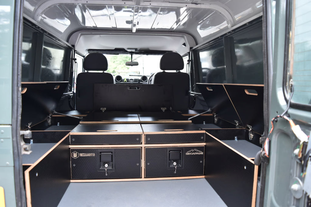 Defender 110 Utility with storage and open cupboards all around the edges, held up with gas struts