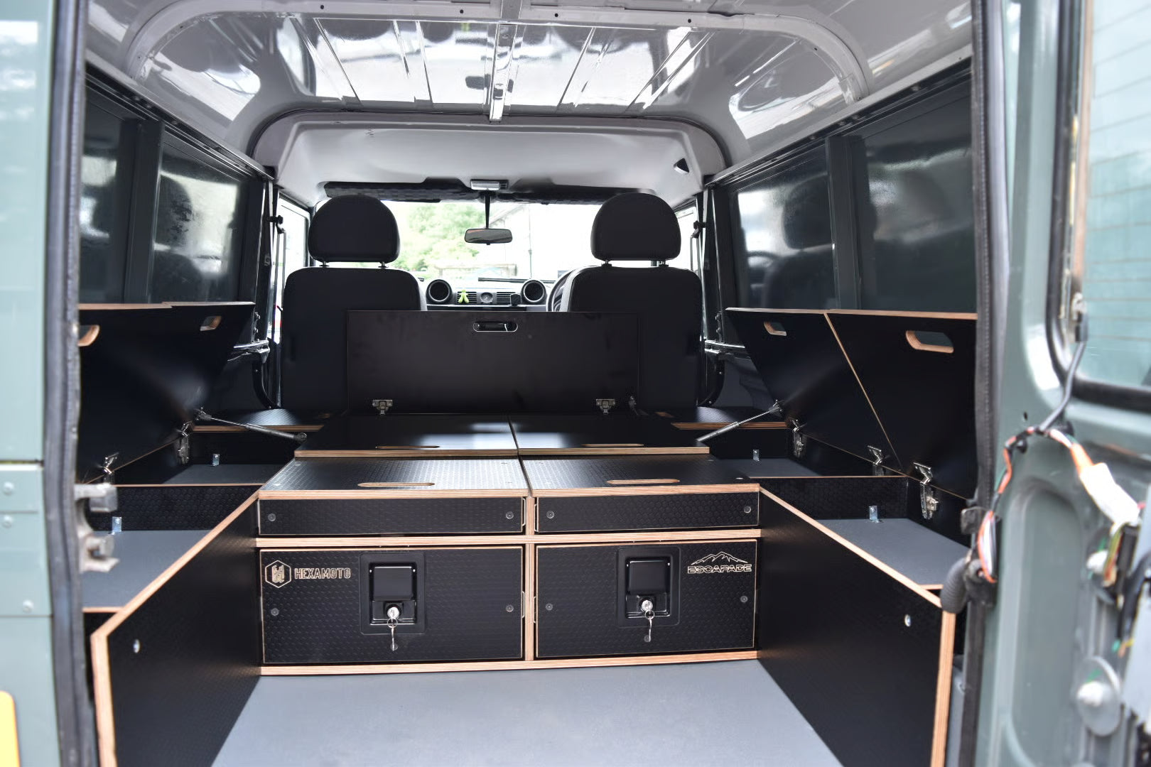 Defender 110 Utility with storage and open cupboards all around the edges, held up with gas struts