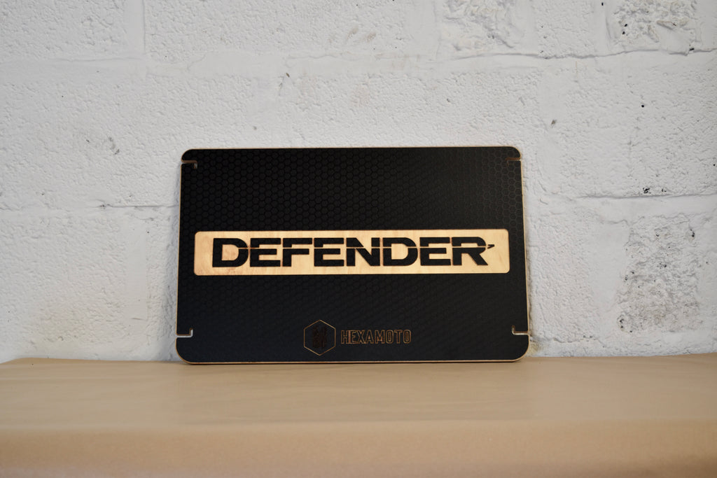 Black table with 'DEFENDER' branding against a white brick wall.