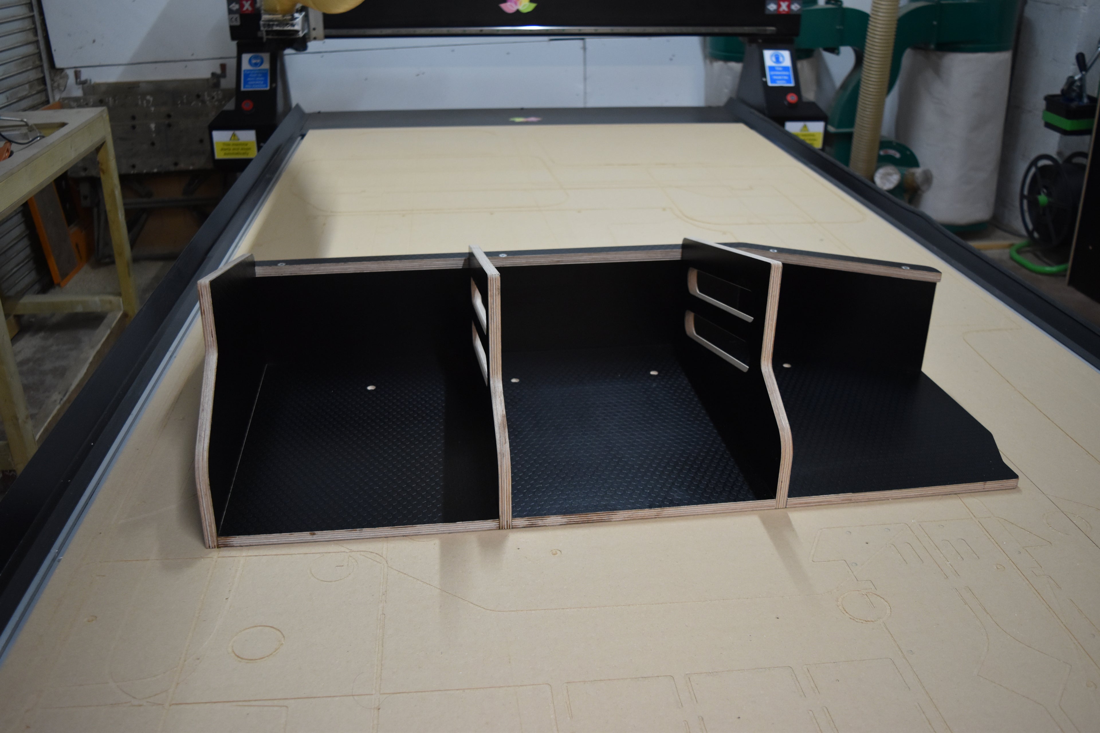 Wooden storage basket with dividers sat on a CNC machine bed