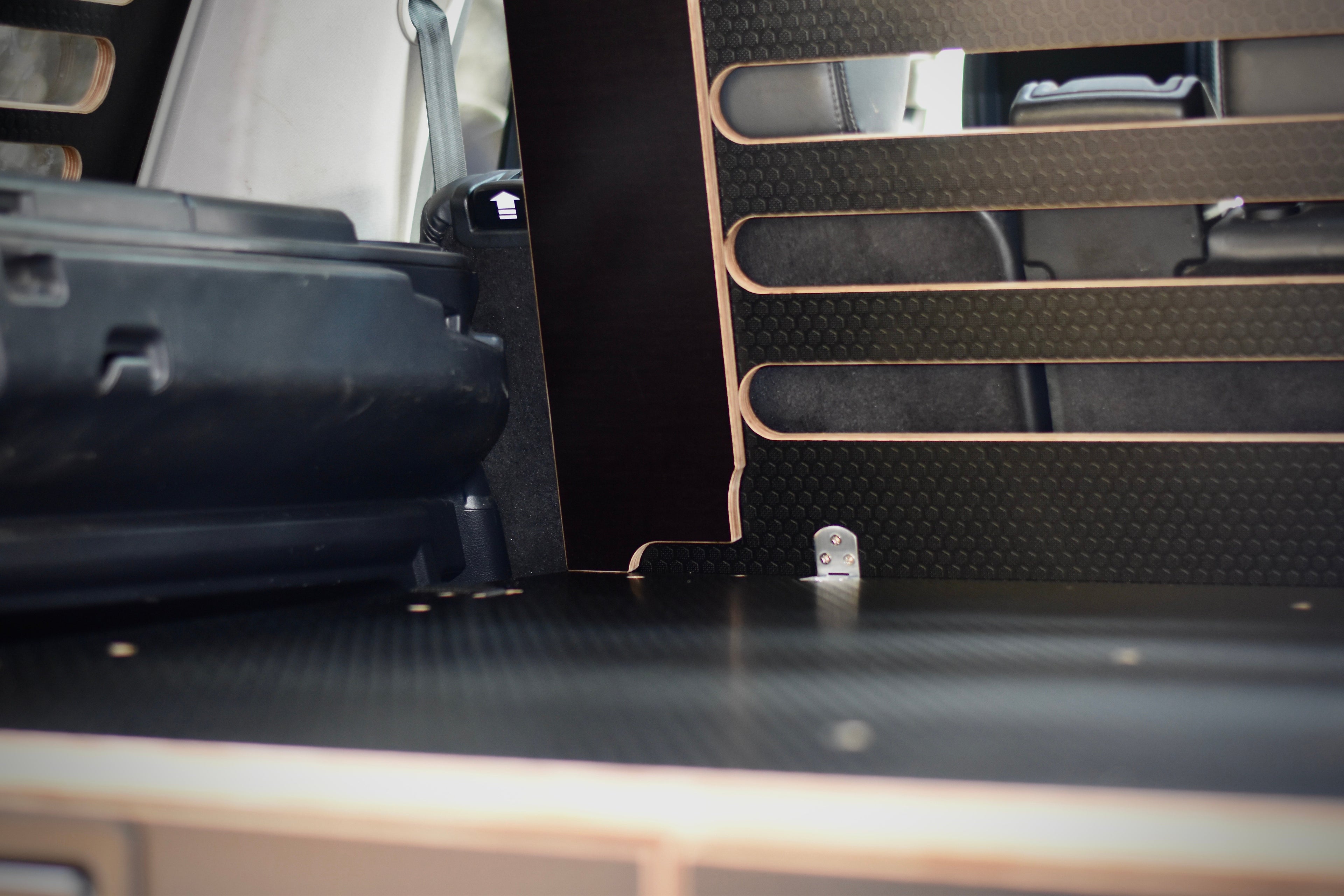 Close-up of a vehicle's cargo area with a black wooden storage system and cargo guard