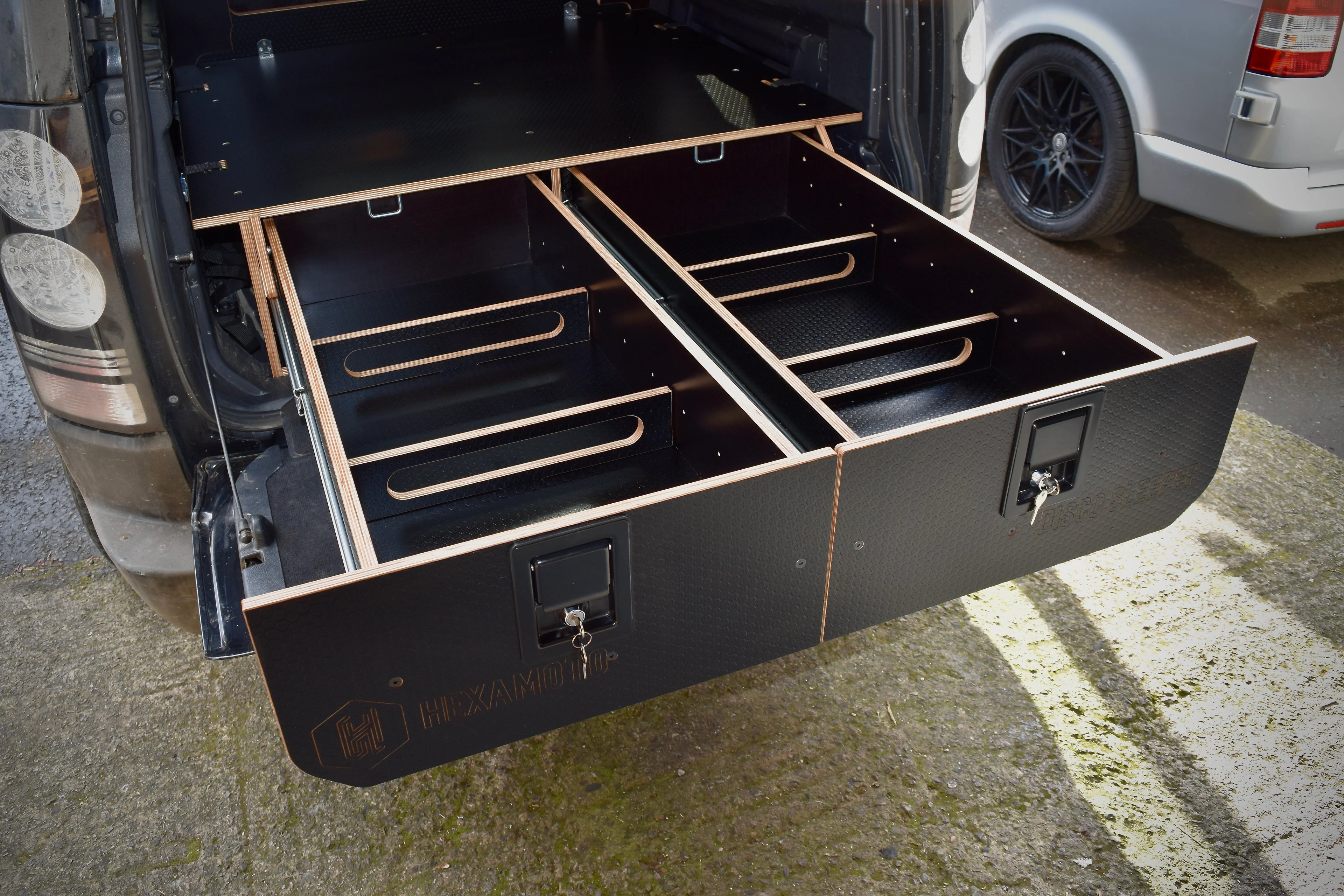 Black wooden drawers pulled out the boot of a vehicle, labelled Hexamoto Disco Sleeper