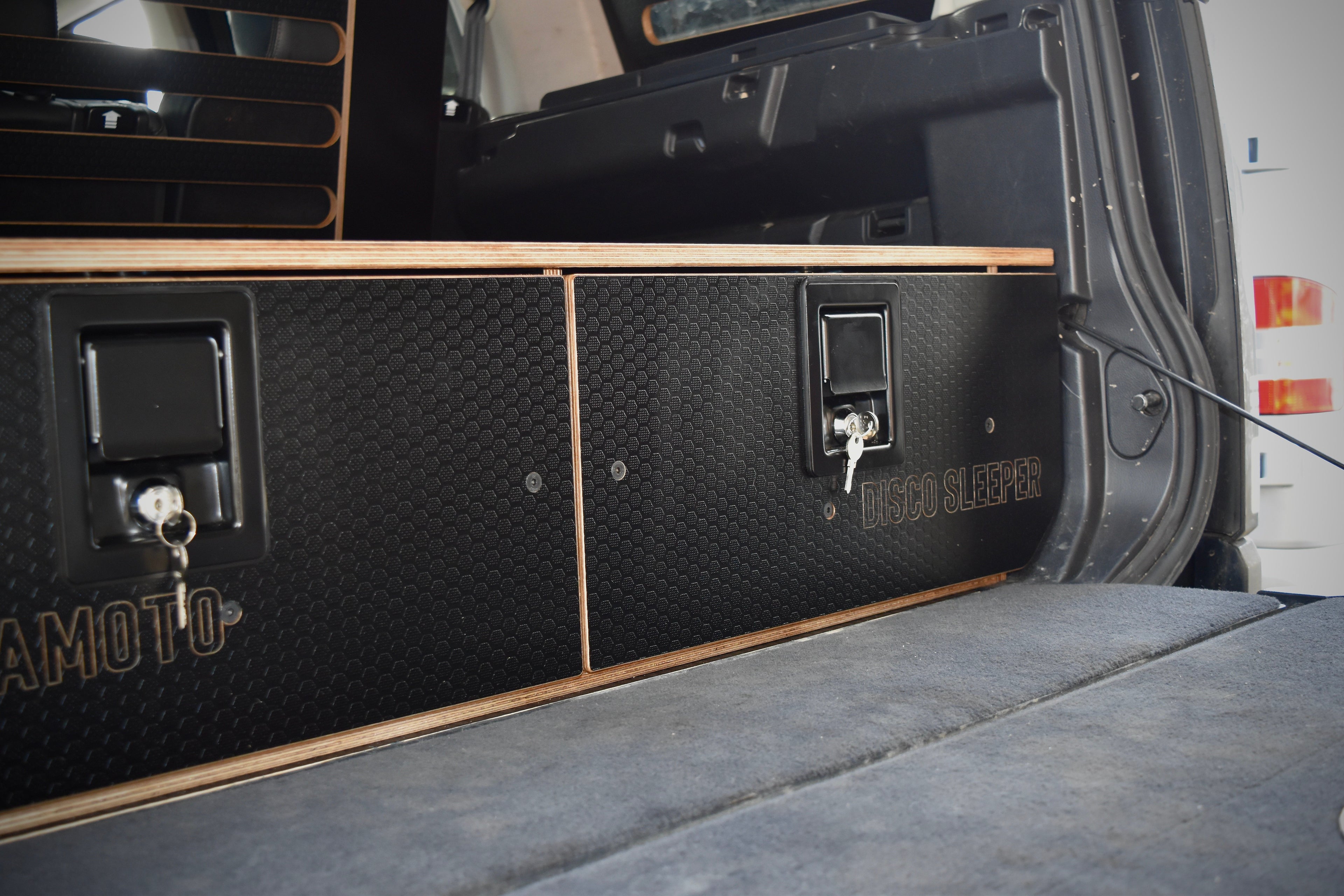Back of a vehicle with a storage compartment labeled 'HEXAMOTO' and 'Disco Sleeper'.