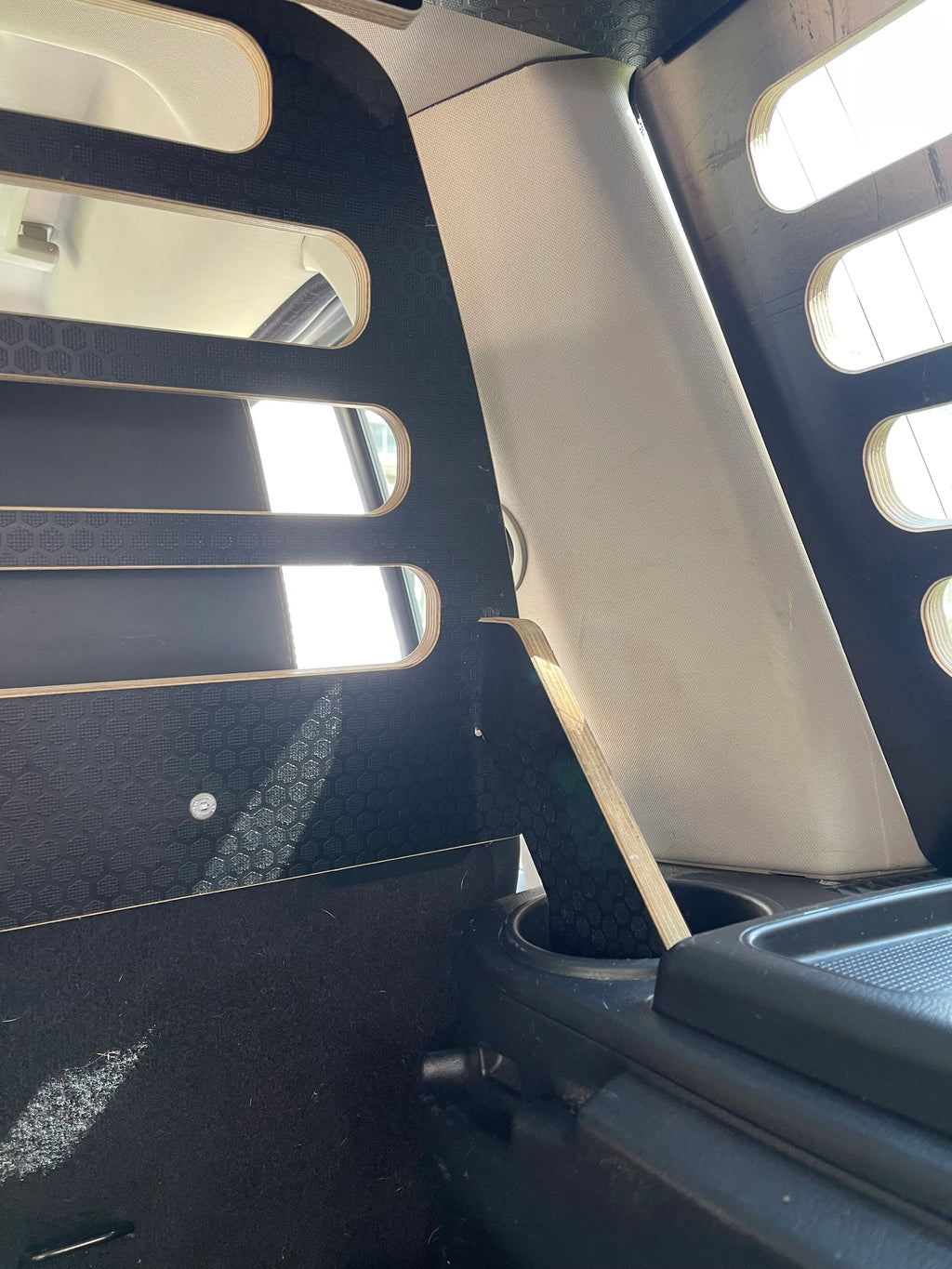 Car interior with a cup holder hole being used to support the Dog Guard with an upright wooden support
