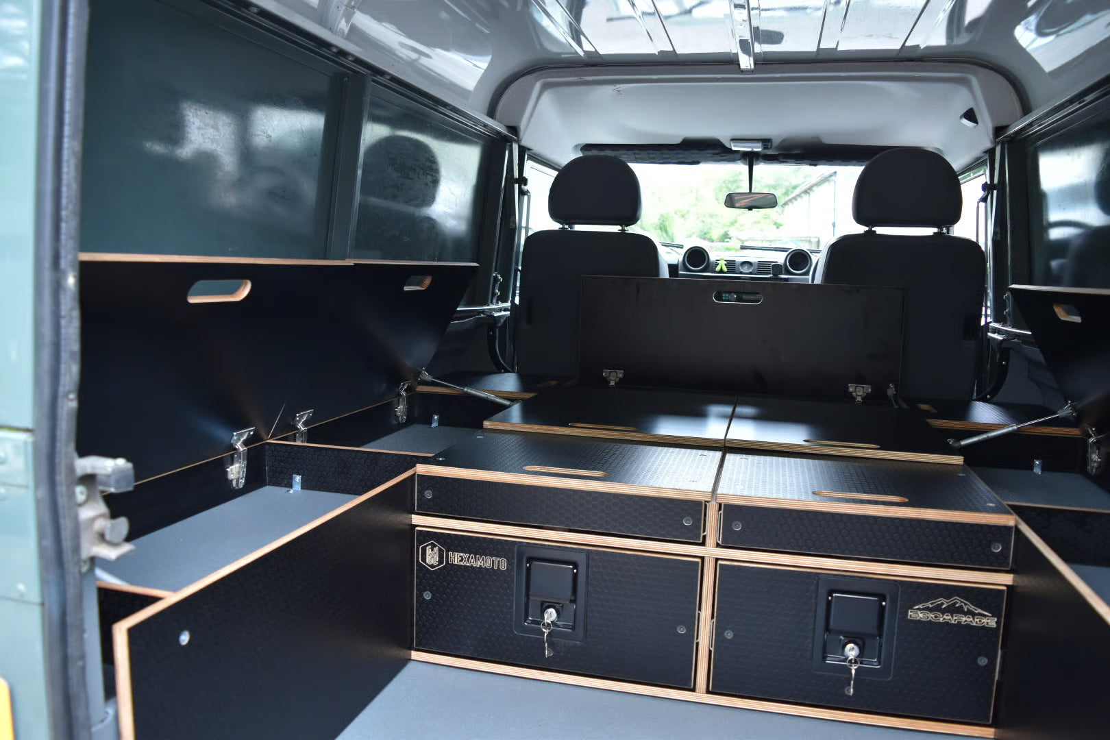 Defender 110 interior with black storage compartments and 'Hexamoto' branding.