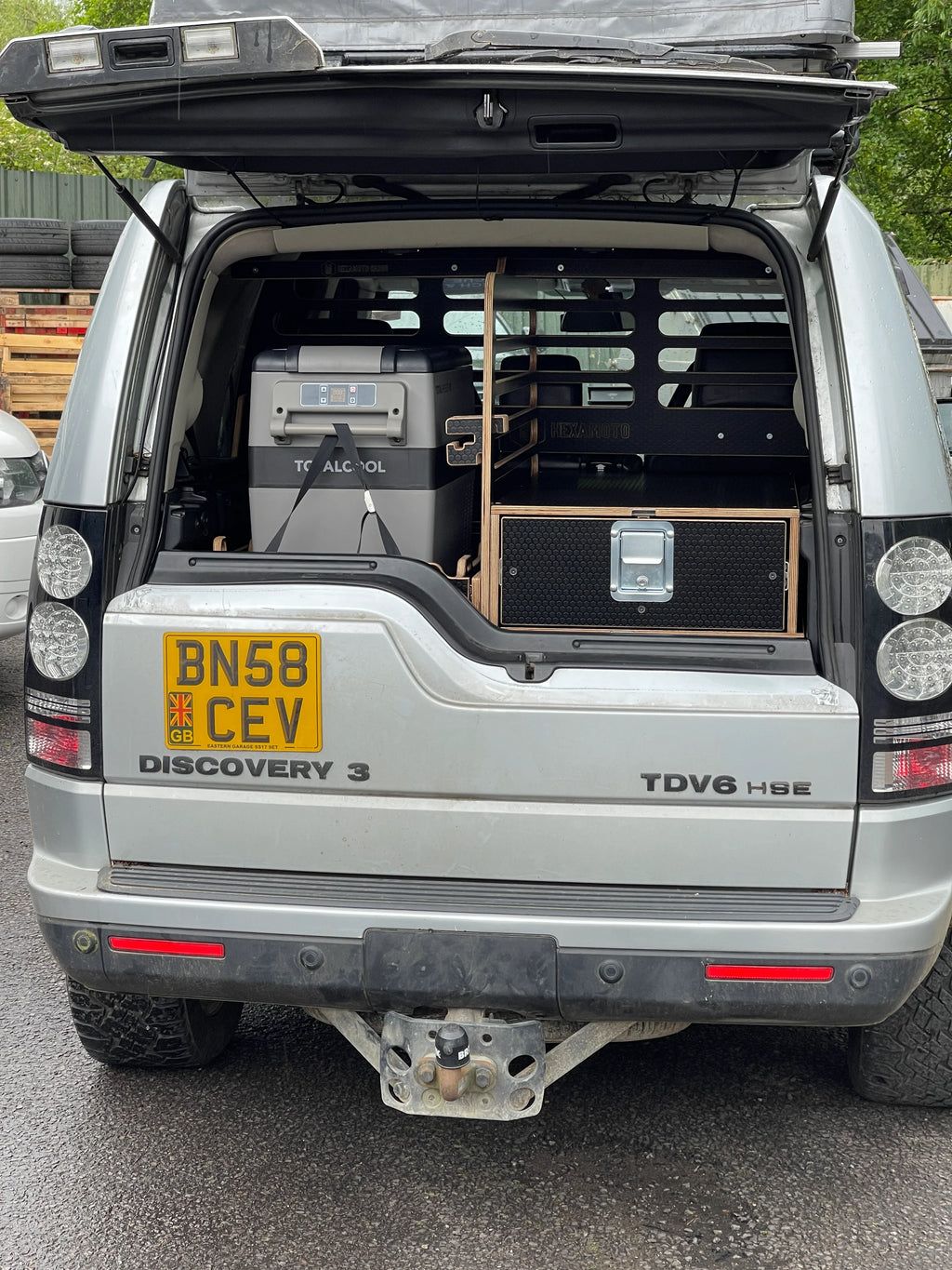 Back of a Land Rover Discovery 3 with bottom hatch closed, showing storage system and cool box in rear
