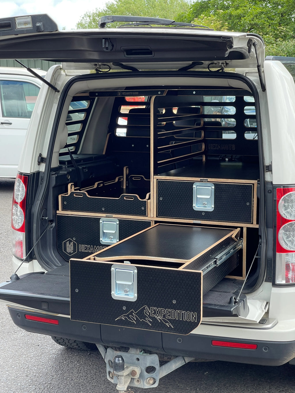 Land Rover Discovery 3 with open cargo area featuring a black storage system labeled 'Hexamoto Expedition'.