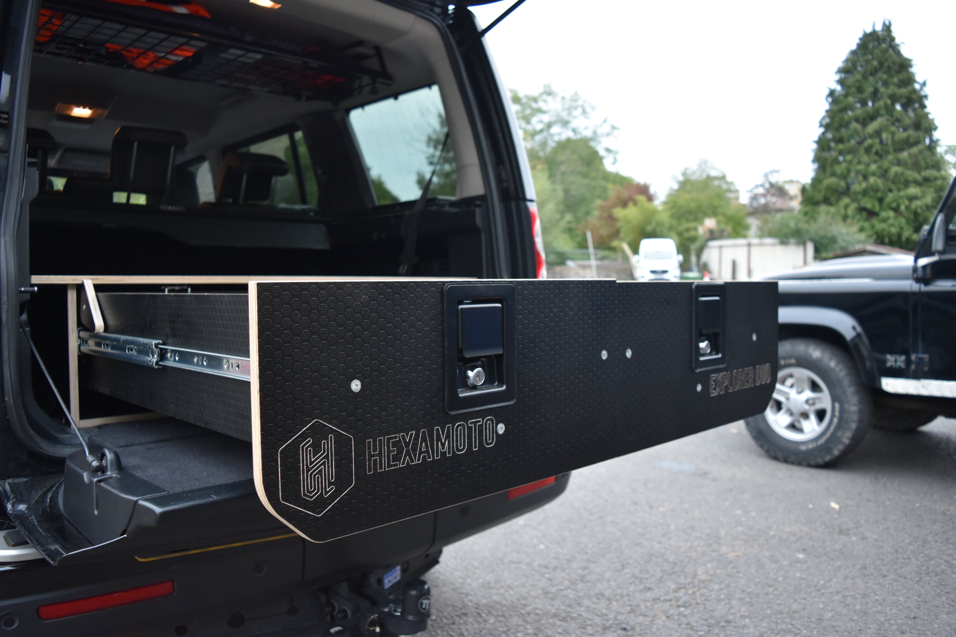 Hexamoto vehicle storage system attached to a black SUV in an outdoor setting.