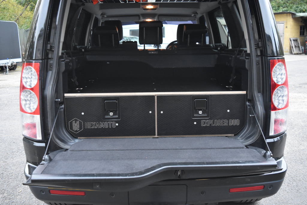 Back of a black SUV with open cargo area and storage compartments.