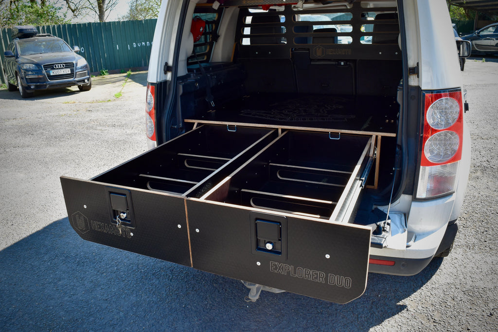 Car with open cargo area showing black storage drawers in a parking lot