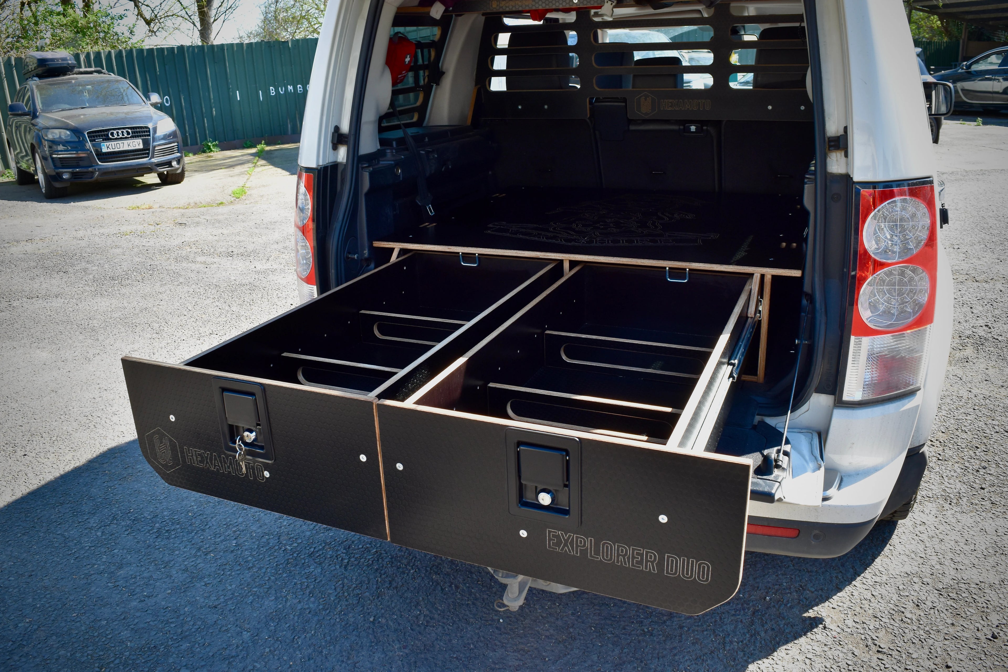 Car with open cargo area showing black storage drawers in a parking lot
