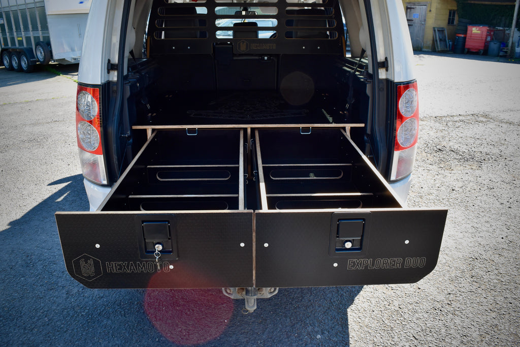 Car with open cargo area showing storage drawers on a concrete surface.
