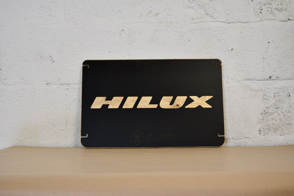 Black woden table with 'HILUX' logo on a white brick wall background