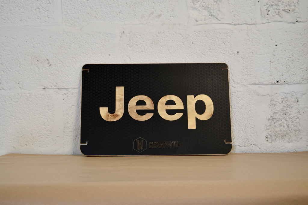 Black table with 'Jeep' logo on a wooden surface against a white brick wall.