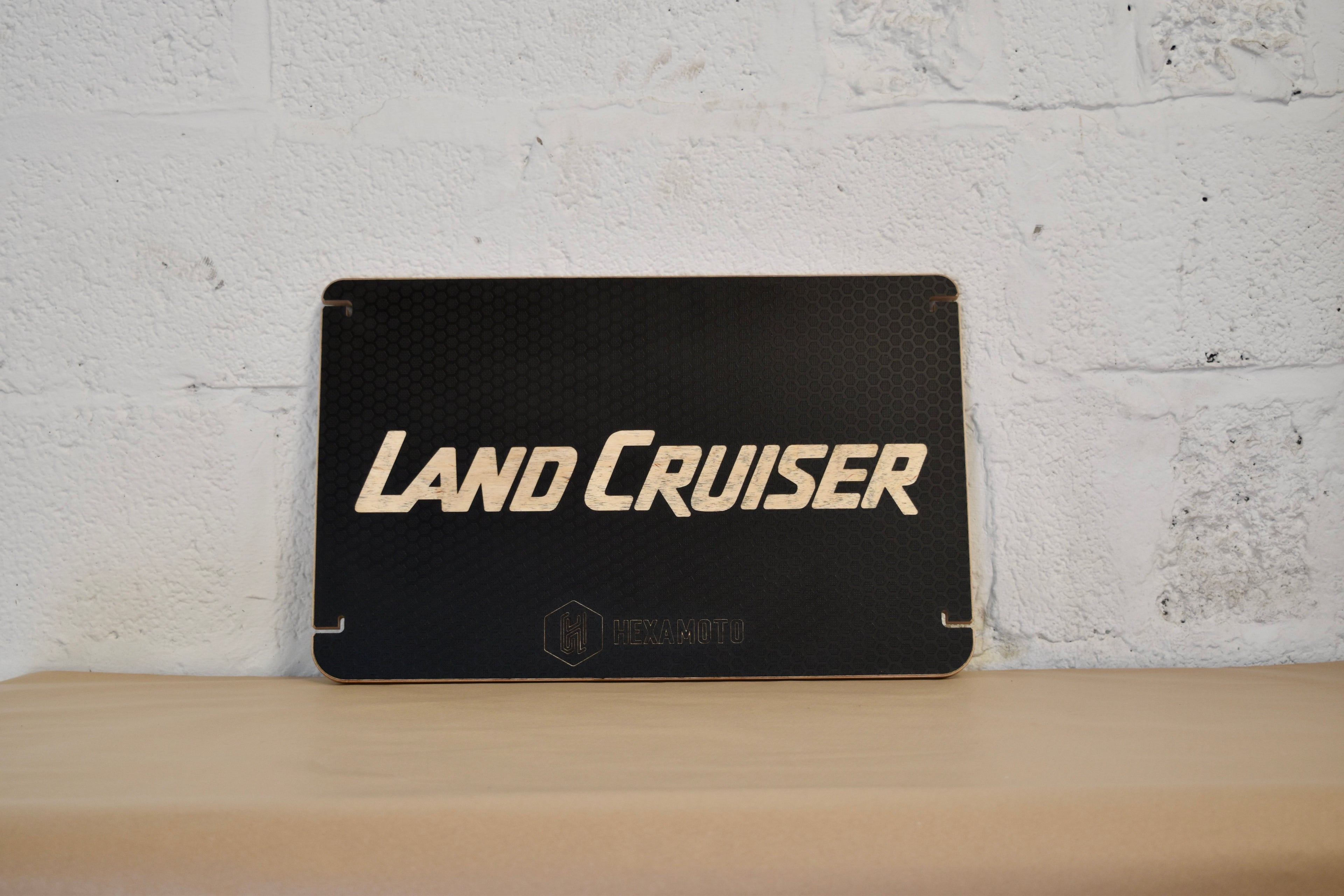 Black table with 'Land Cruiser' branding on a wooden surface and white brick wall background