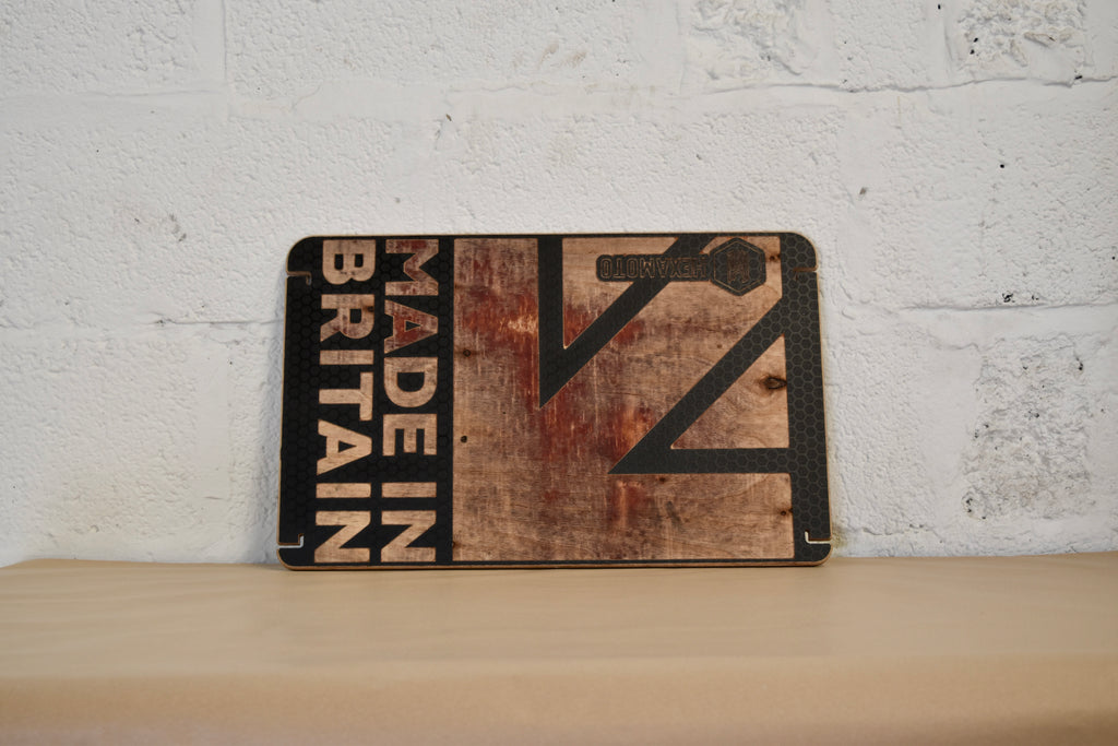 Wooden table with 'Made in Britain' text design on a white brick wall background.