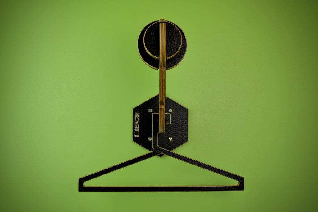 Wooden hanger and helmet mounting system fitted onto a green wall