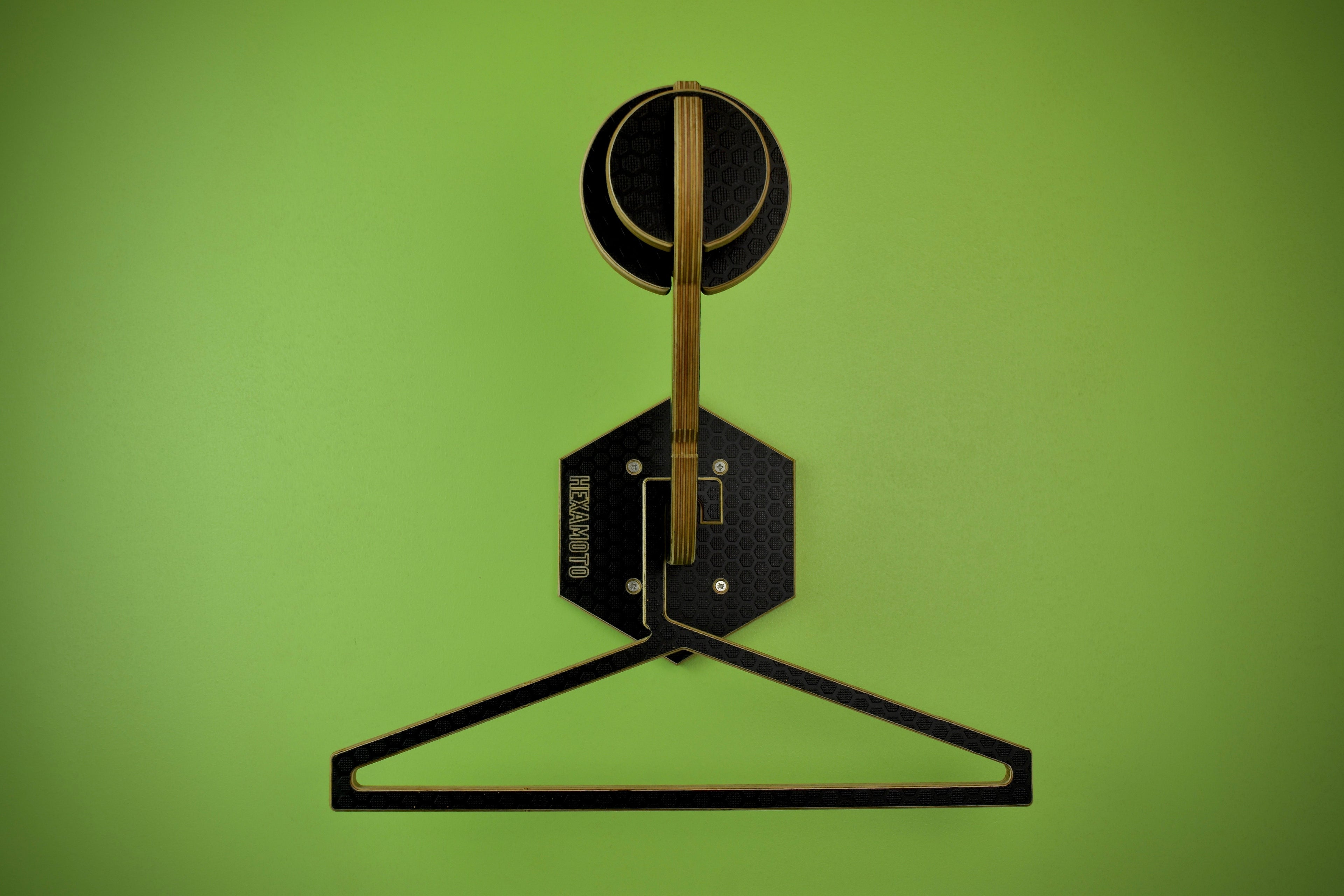 Wooden hanger and helmet mounting system fitted onto a green wall