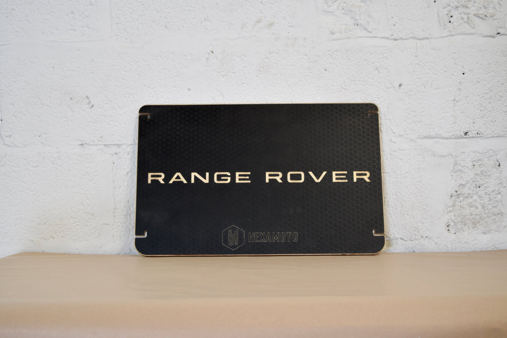 Black Range Rover table on a wooden surface with a white brick wall background