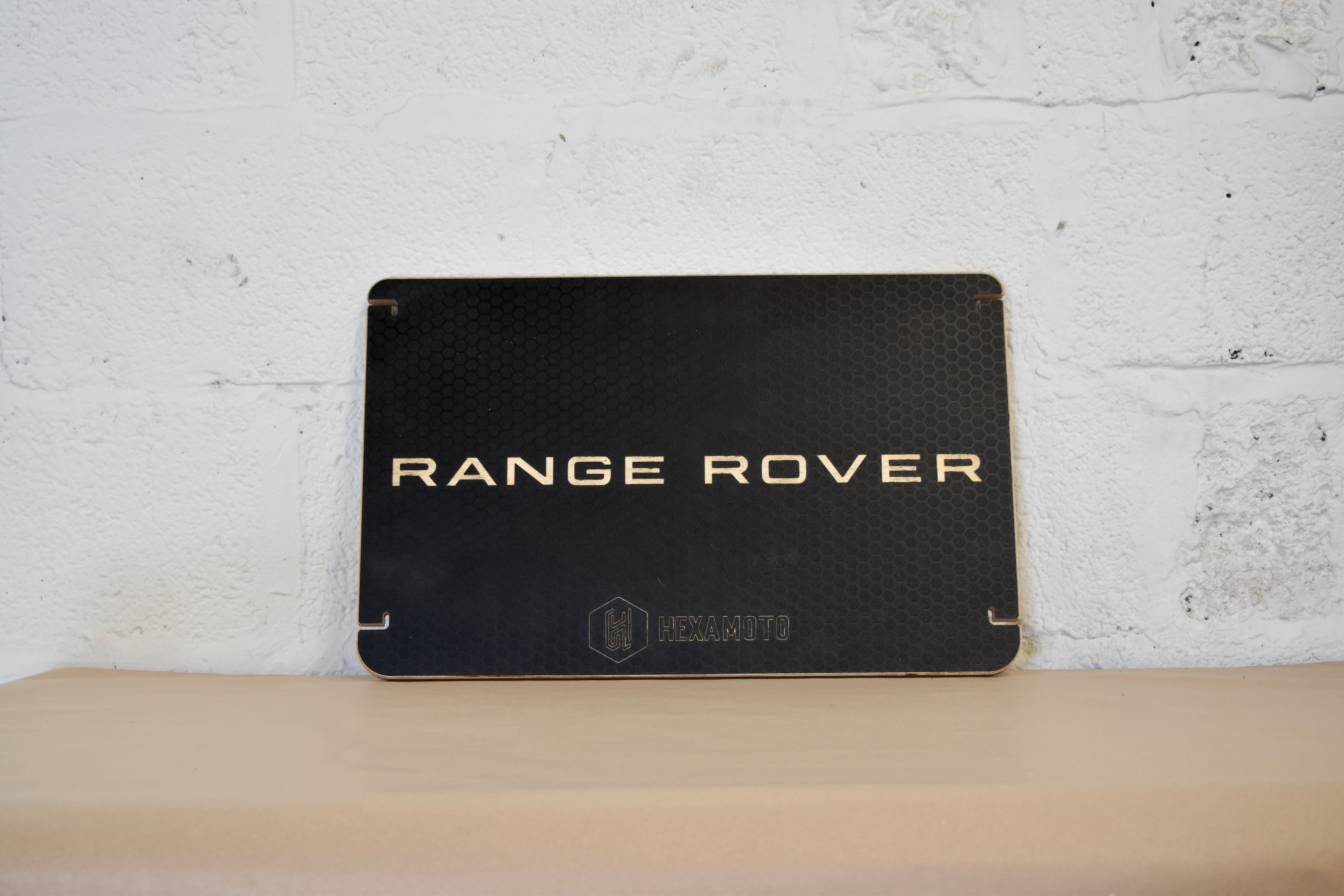 Black Range Rover table on a wooden surface with a white brick wall background