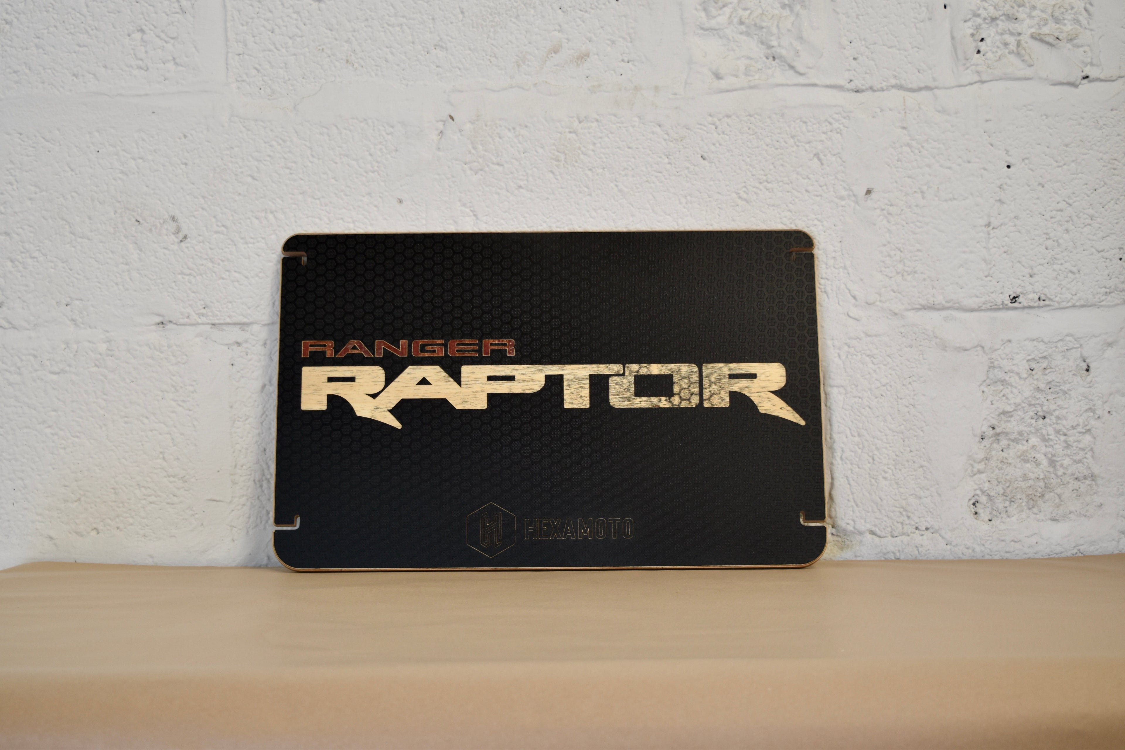Black 'Ranger Raptor' table on a wooden surface with a white brick wall background