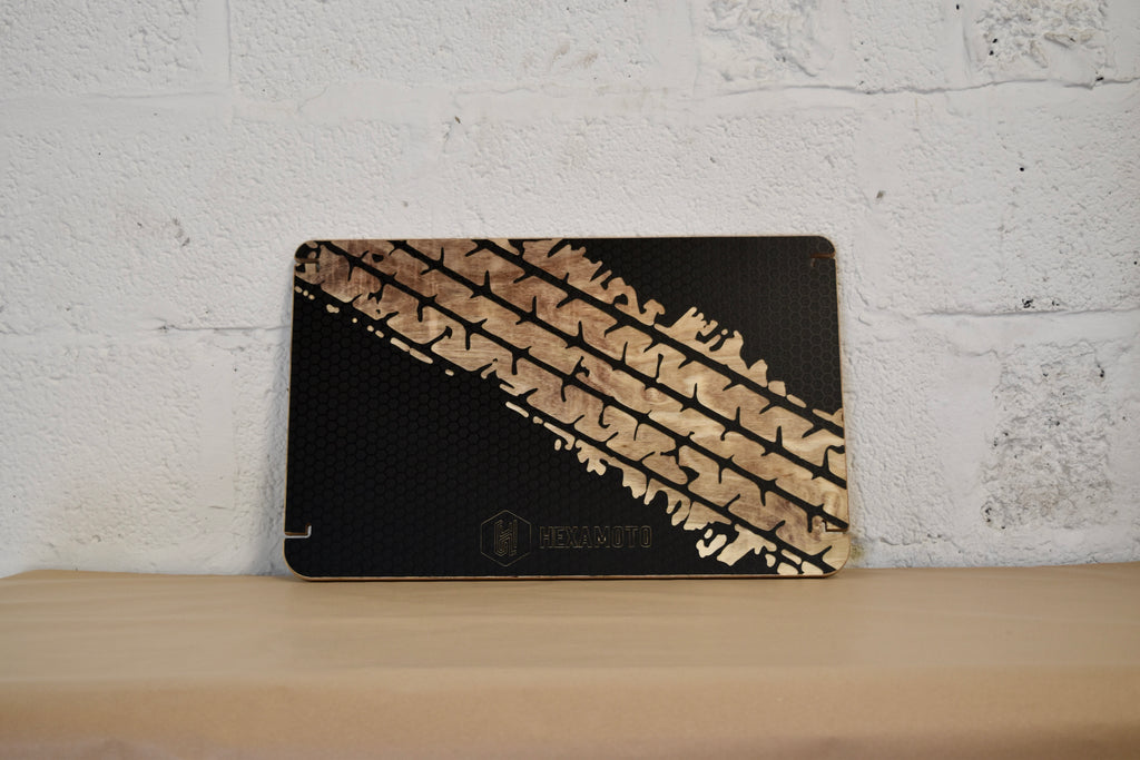 Black table with tyre track design on a wooden surface with a white brick wall background