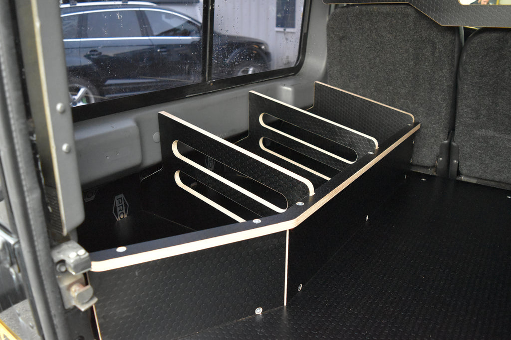 Black wooden storage system in back of a Land Rover Defender, including the Hexamoto Utility Storage Basket
