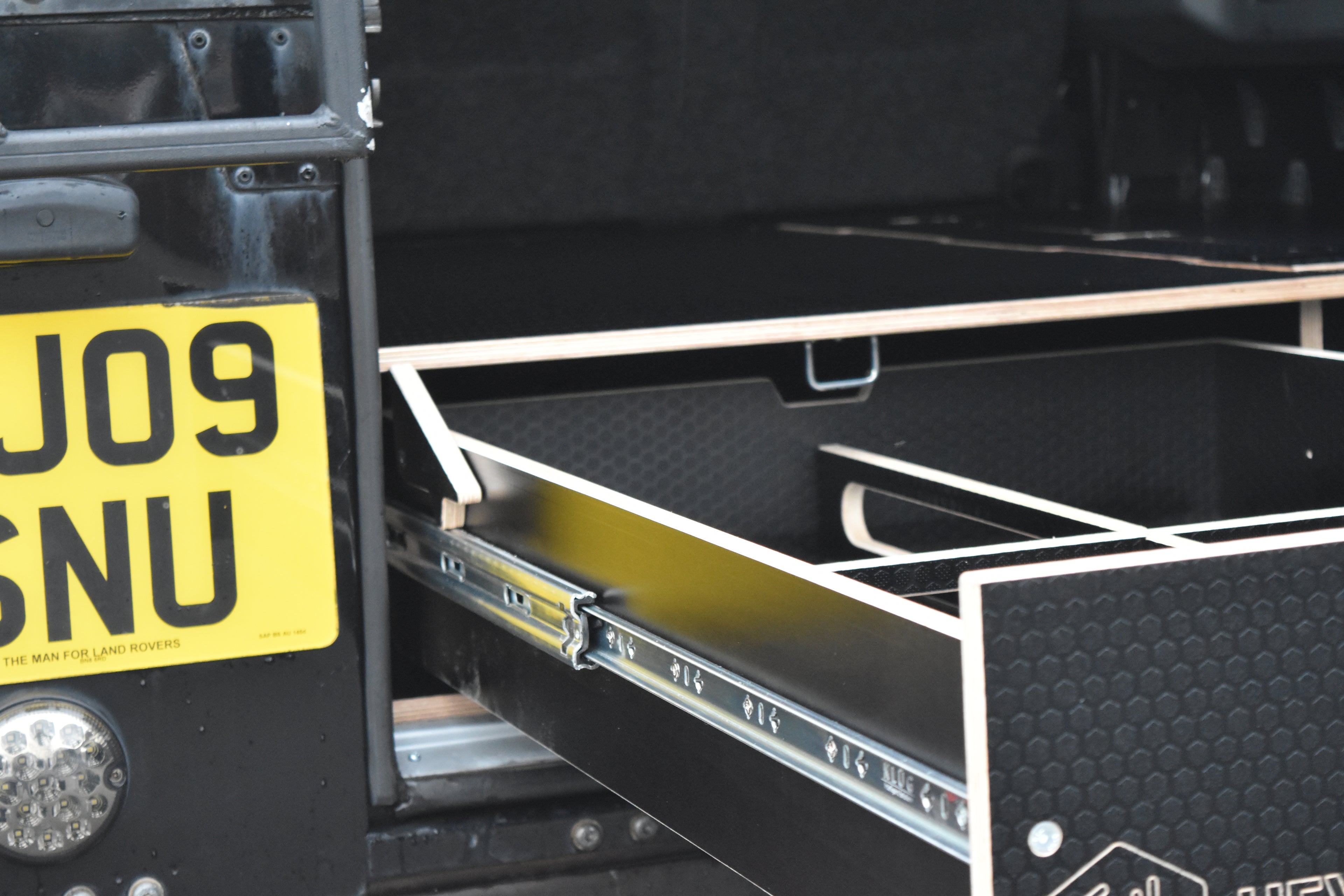 Boot of a Land Rover Defender 110 showing drawer system side with runner in view