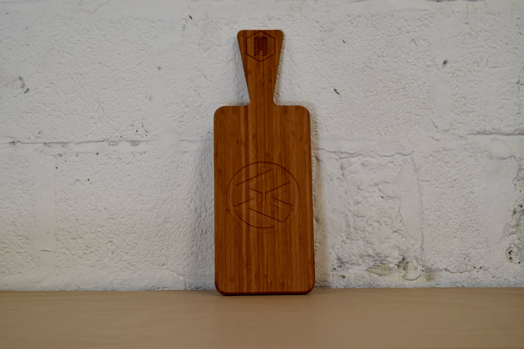 Bamboo chopping board with VW logo engraved placed on a white brick background