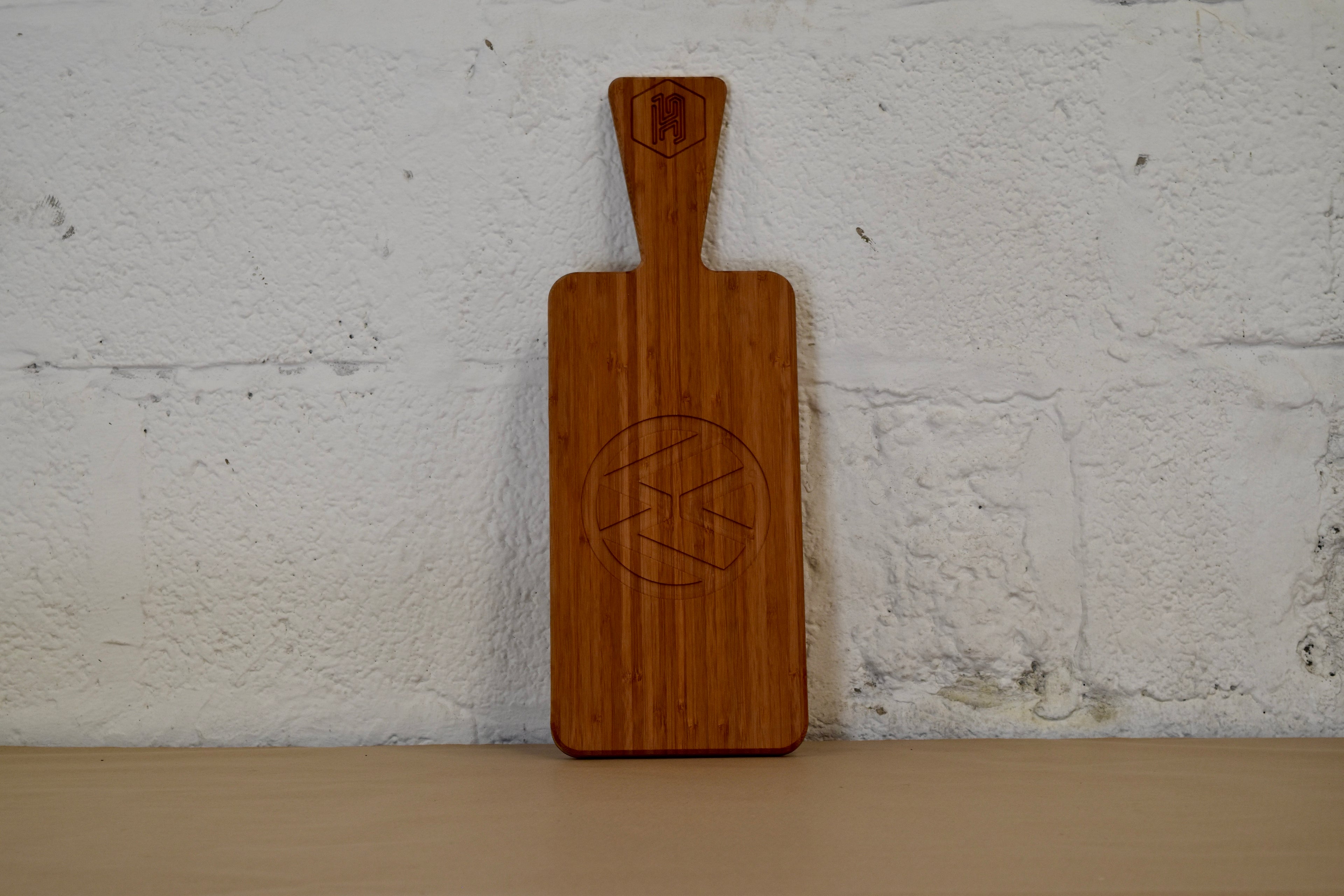 Bamboo chopping board with VW logo engraved placed on a white brick background