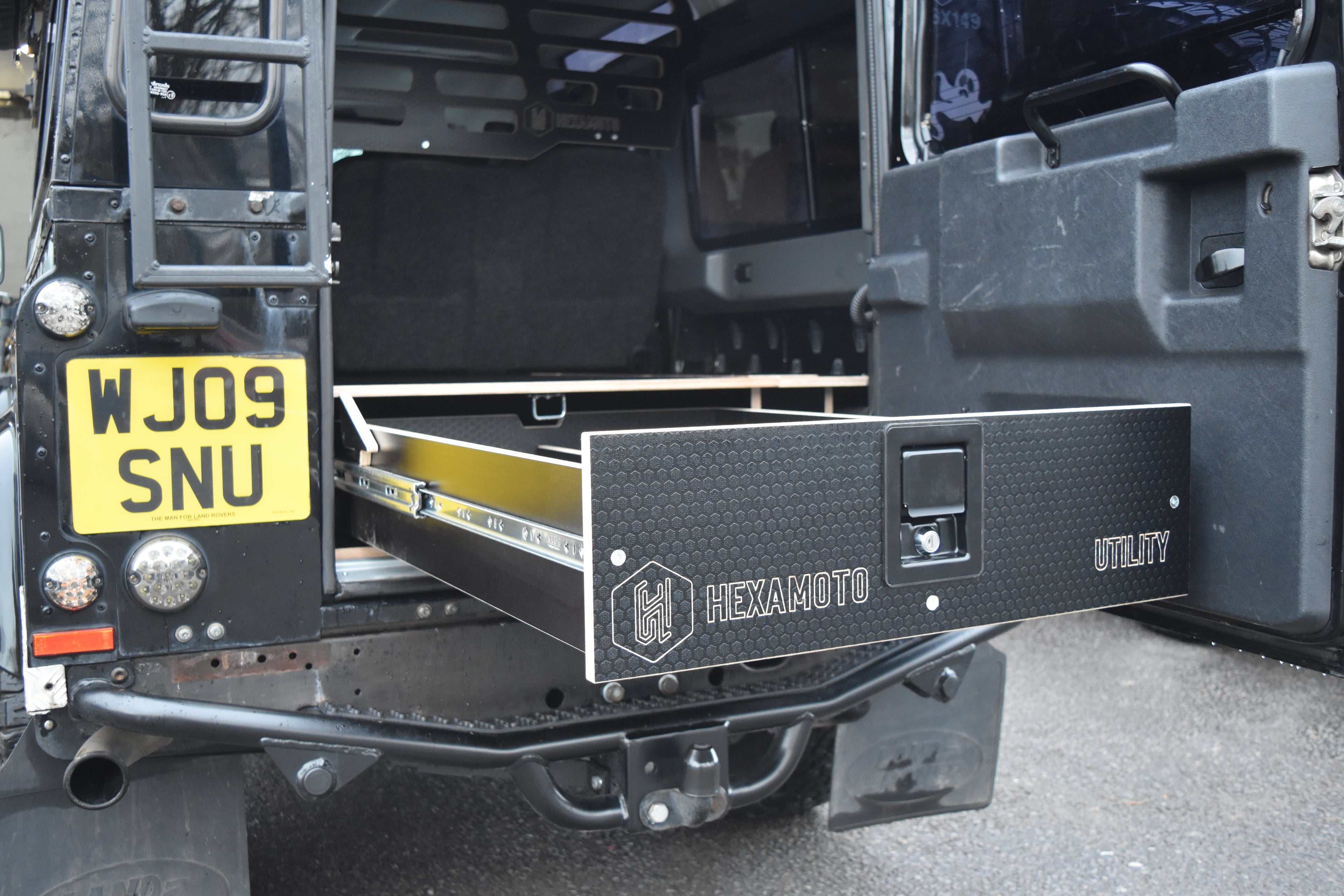 Hexamoto vehicle with a black storage drawer and visible license plate.
