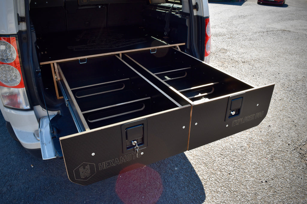 Car with open storage drawers labeled 'Hexamoto Explorer Duo' on a pavement background