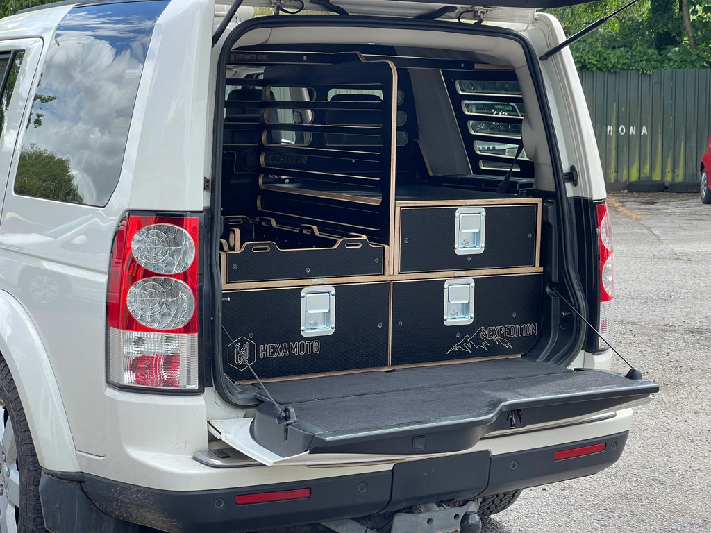 Back of a white SUV with open cargo area featuring black storage drawers