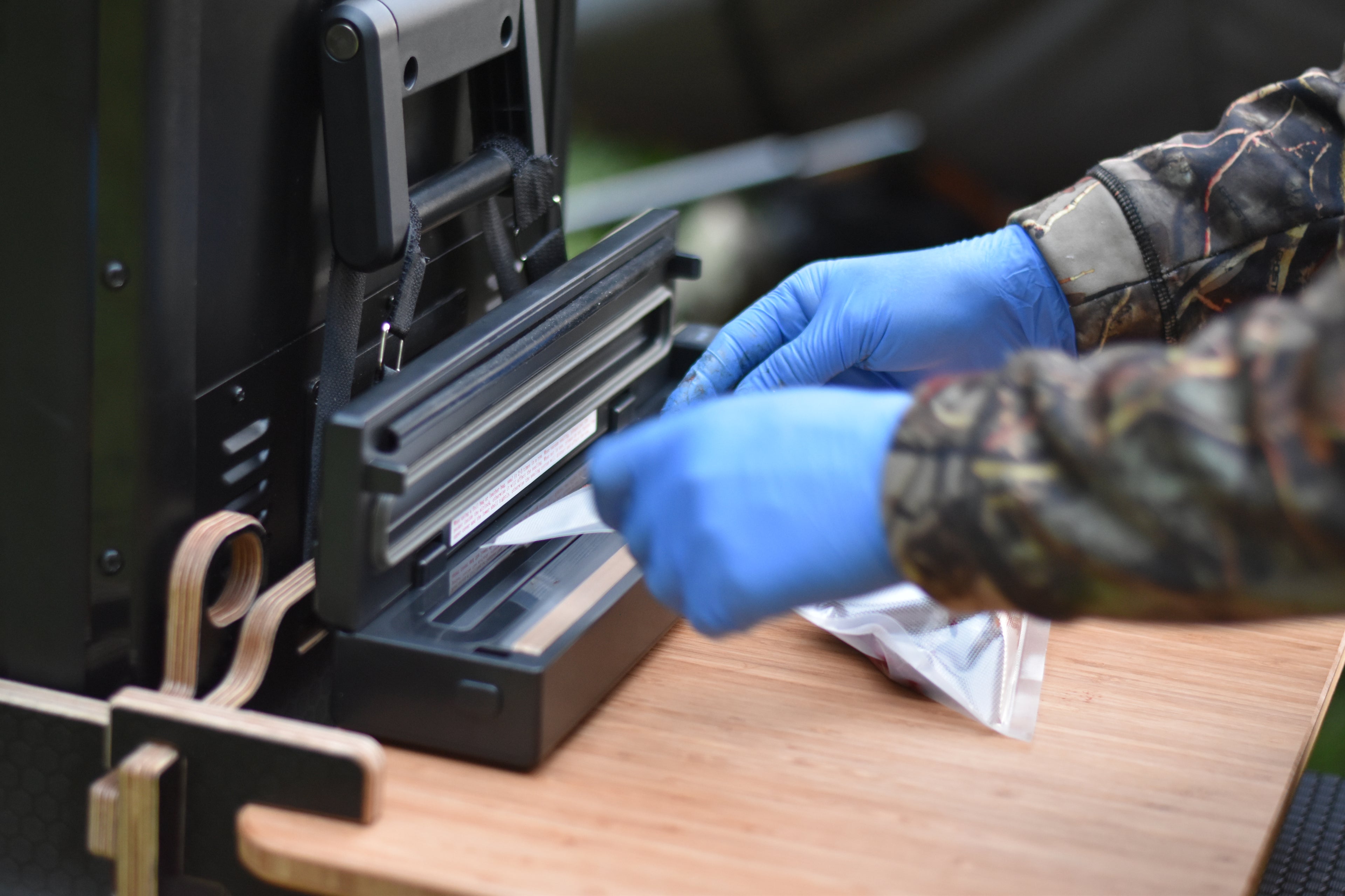 Person wearing gloves using a vacuum packing device on a wooden surface